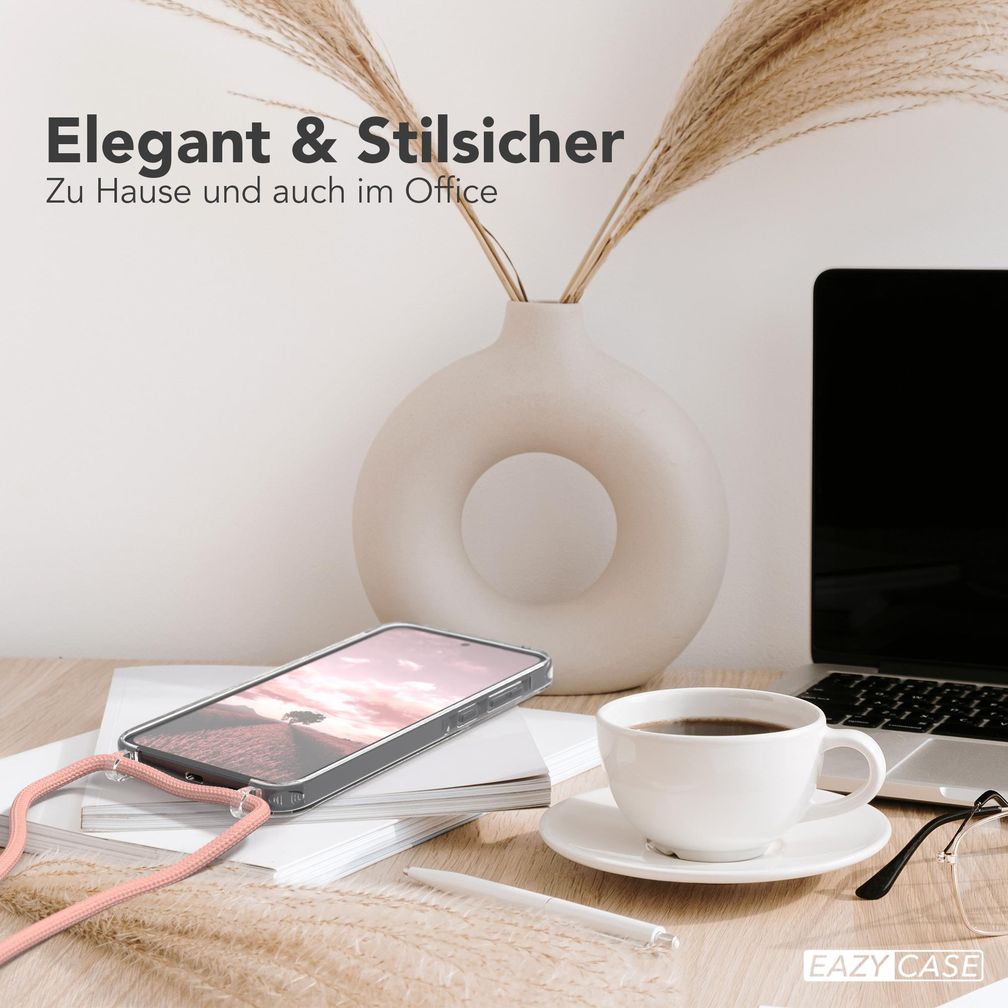 Ein Telefon mit Hülle, Kaffee und Laptop auf einem Schreibtisch. Vase mit Pampasgras.