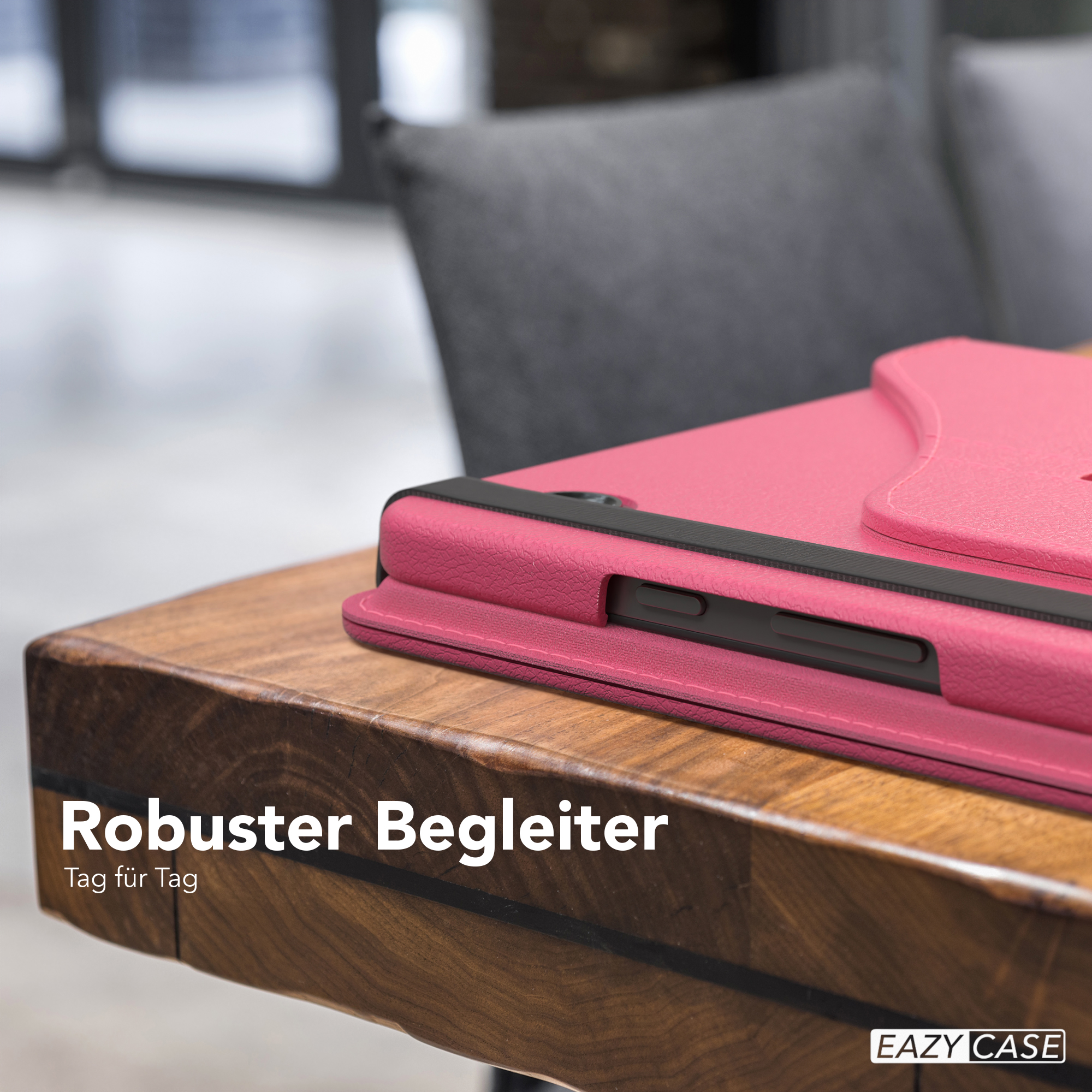 Rosa Tablethülle auf einem Holztisch. Im Hintergrund ein grauer Stuhl.