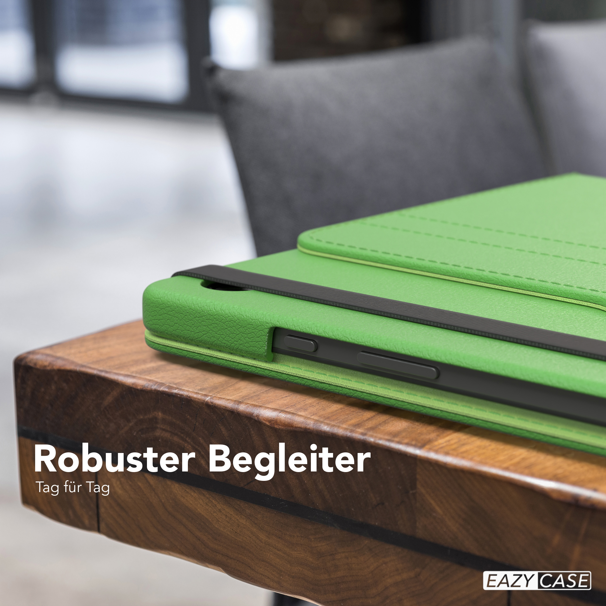 Grüne Tablet-Hülle auf Holztisch. Text sagt 'Robuster Begleiter'. Ein grauer Stuhl im Hintergrund.