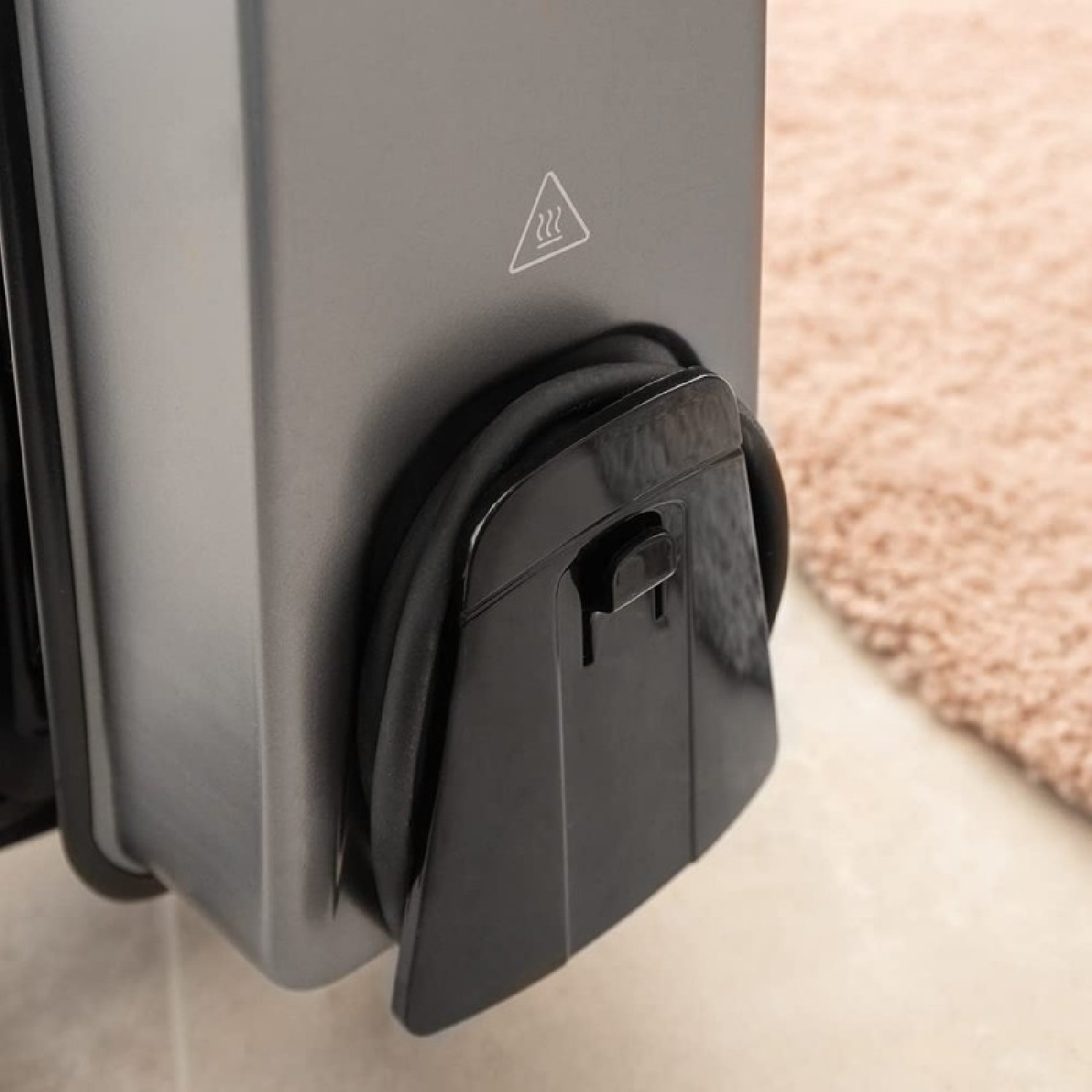 Zbliżenie czarnego kabla wpiętego do ciemnoszarego urządzenia, z beżowym dywanem w tle.