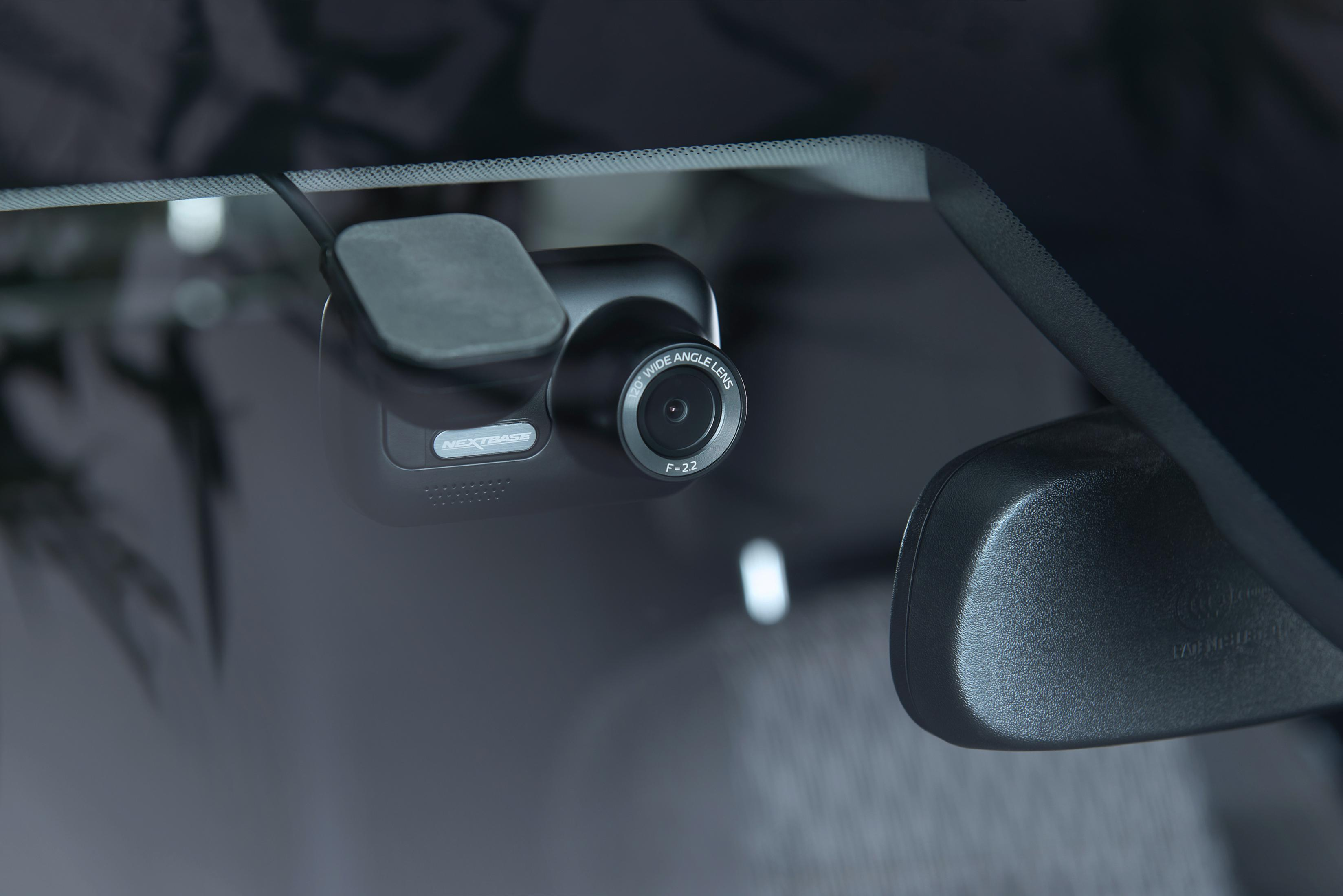 Schwarze Dashcam an der Windschutzscheibe montiert. Die Kamera hat ein Objektiv und zeigt 'Nextbase'.