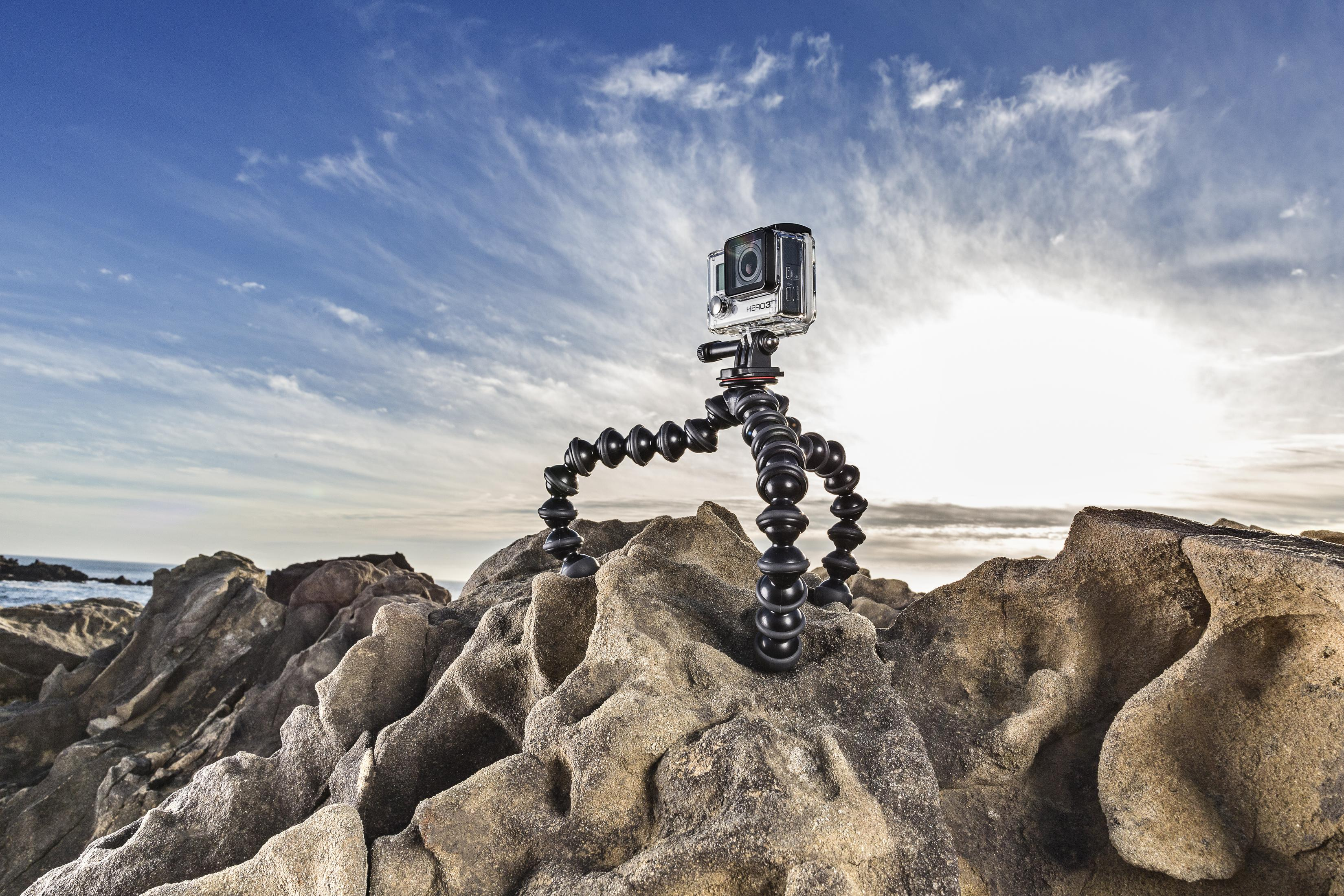 Una fotocamera su un treppiede flessibile è su una roccia. Il cielo è blu.