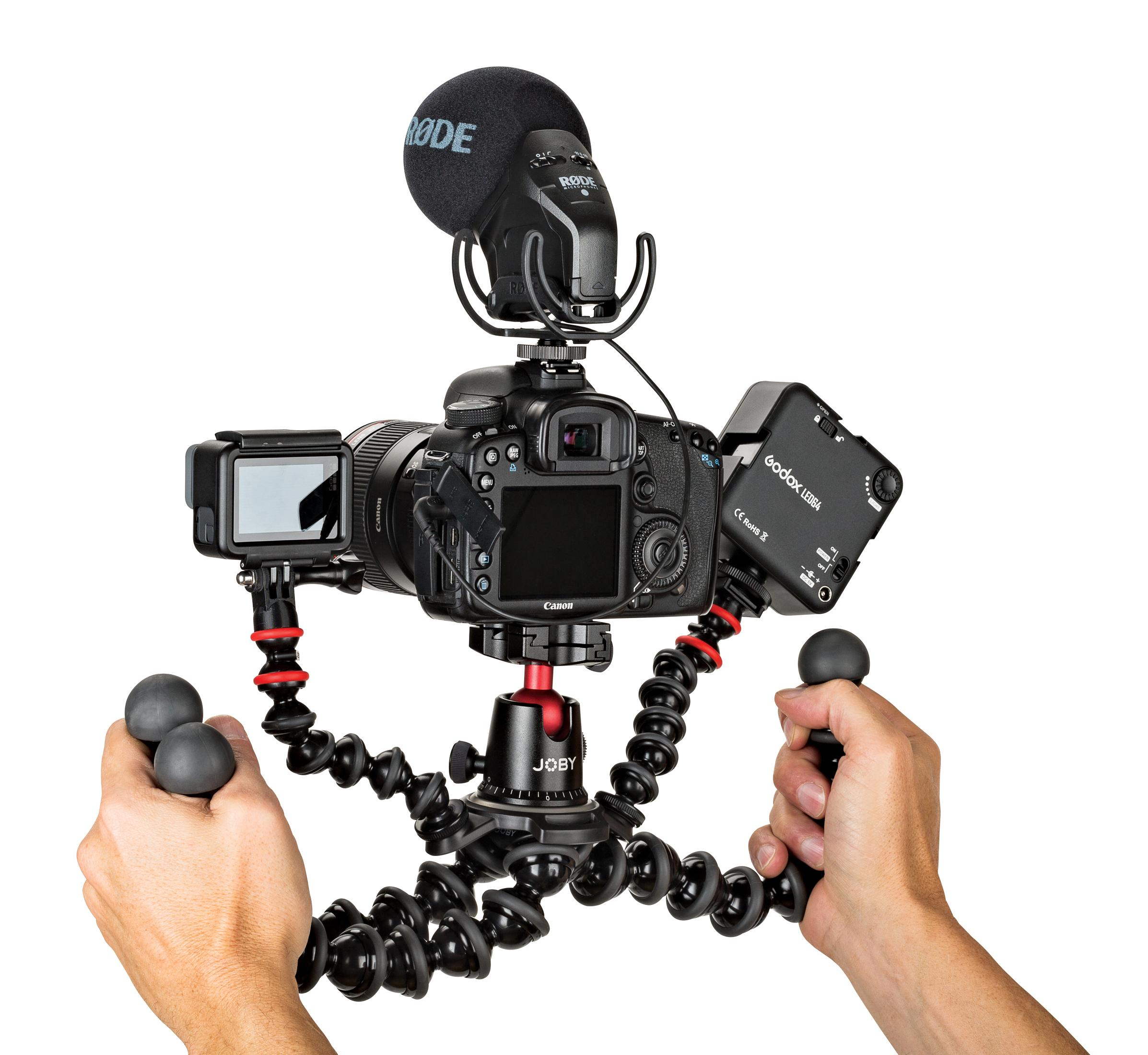 Configurazione fotocamera con microfono, luce e treppiede con gambe flessibili. Sfondo bianco.