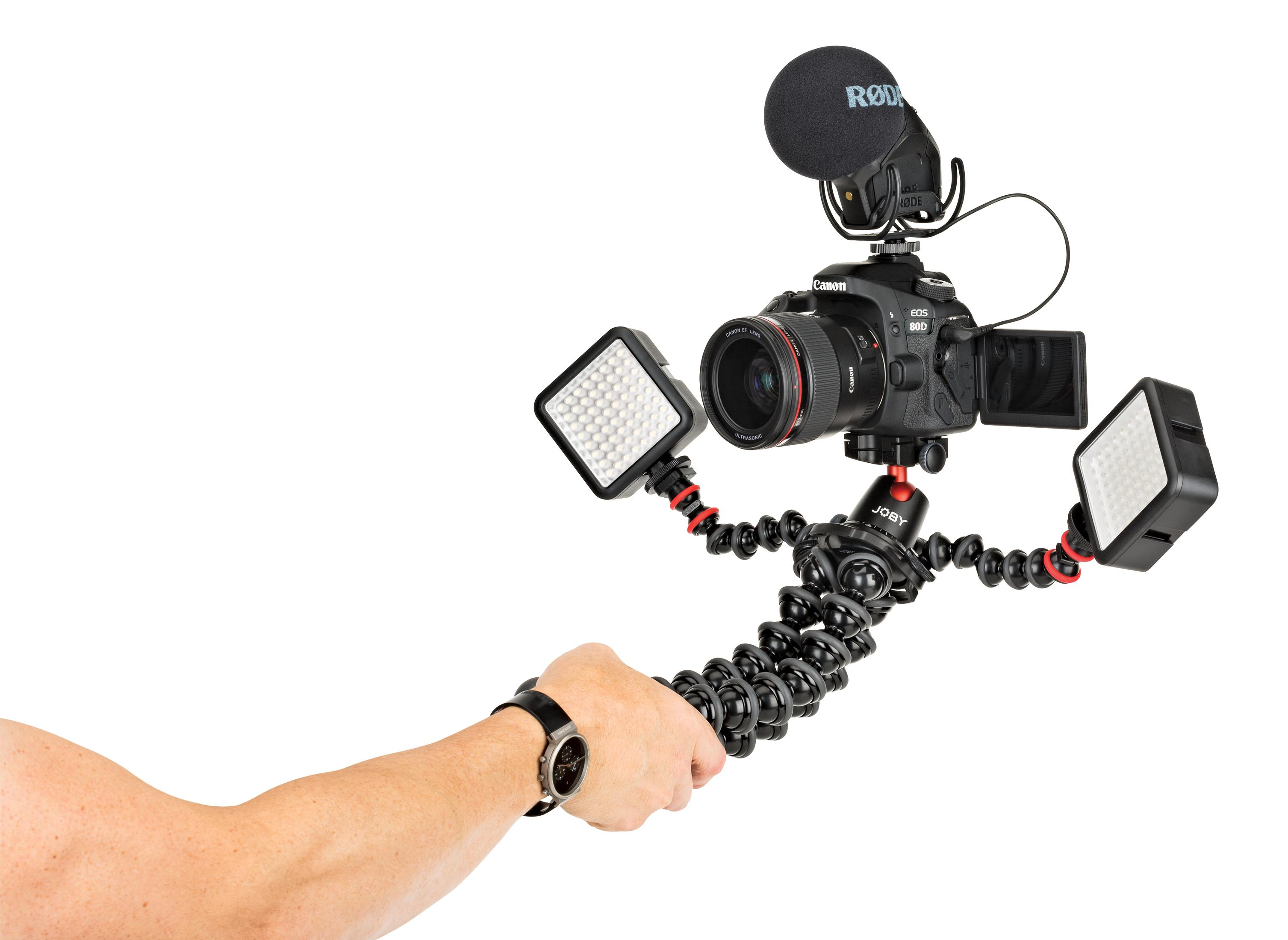 Una persona che tiene una fotocamera con accessori su un treppiede flessibile. Include microfono e luci.