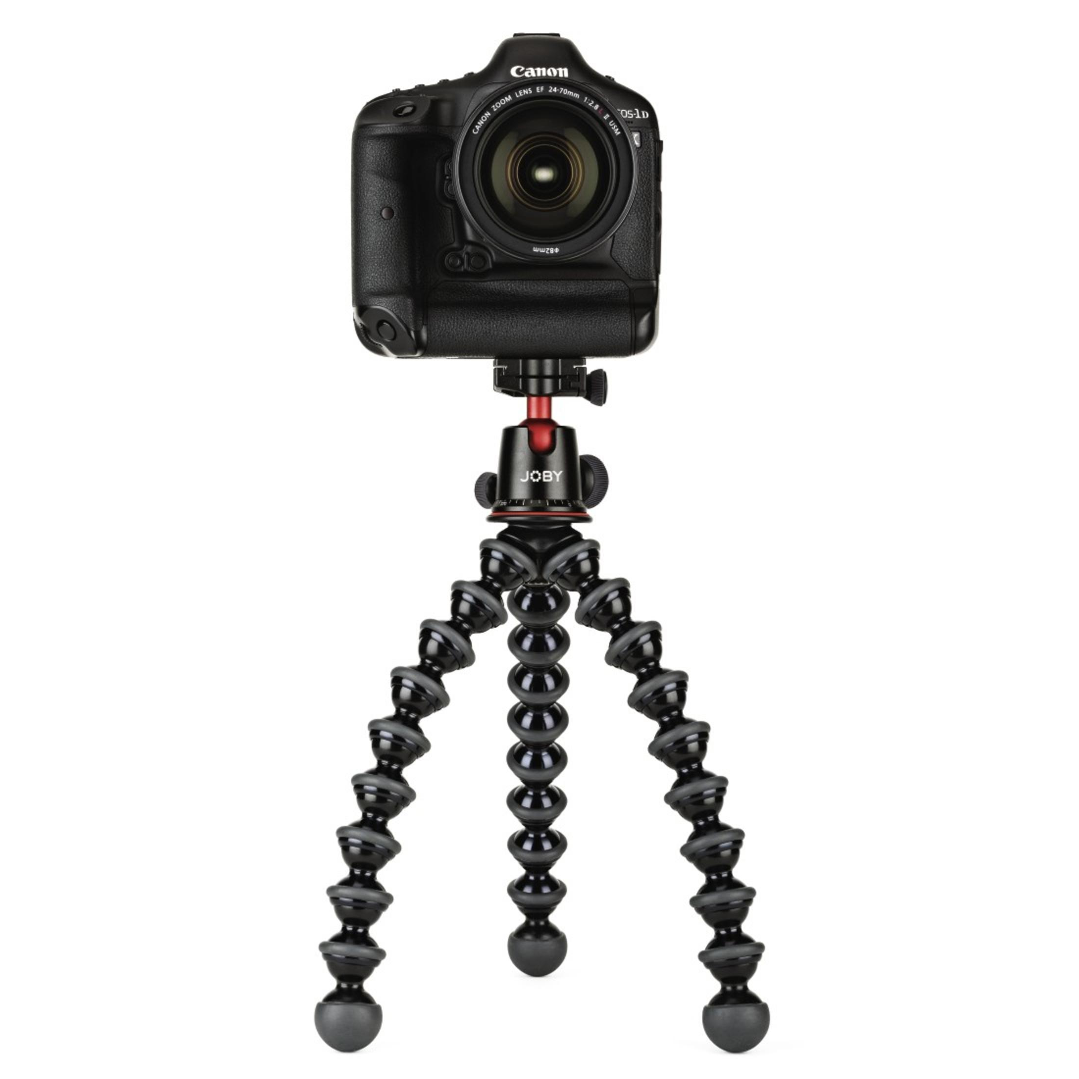 Fotocamera su un treppiede pieghevole. Fotocamera nera, treppiede con gambe flessibili, sfondo bianco.