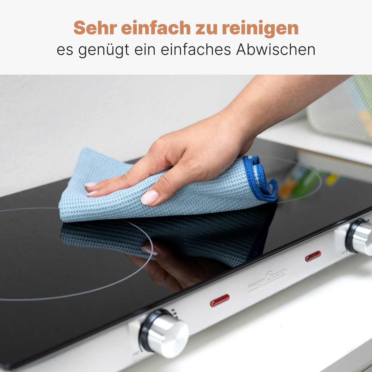 Ręka czyszcząca czarną kuchenkę niebieską szmatką.