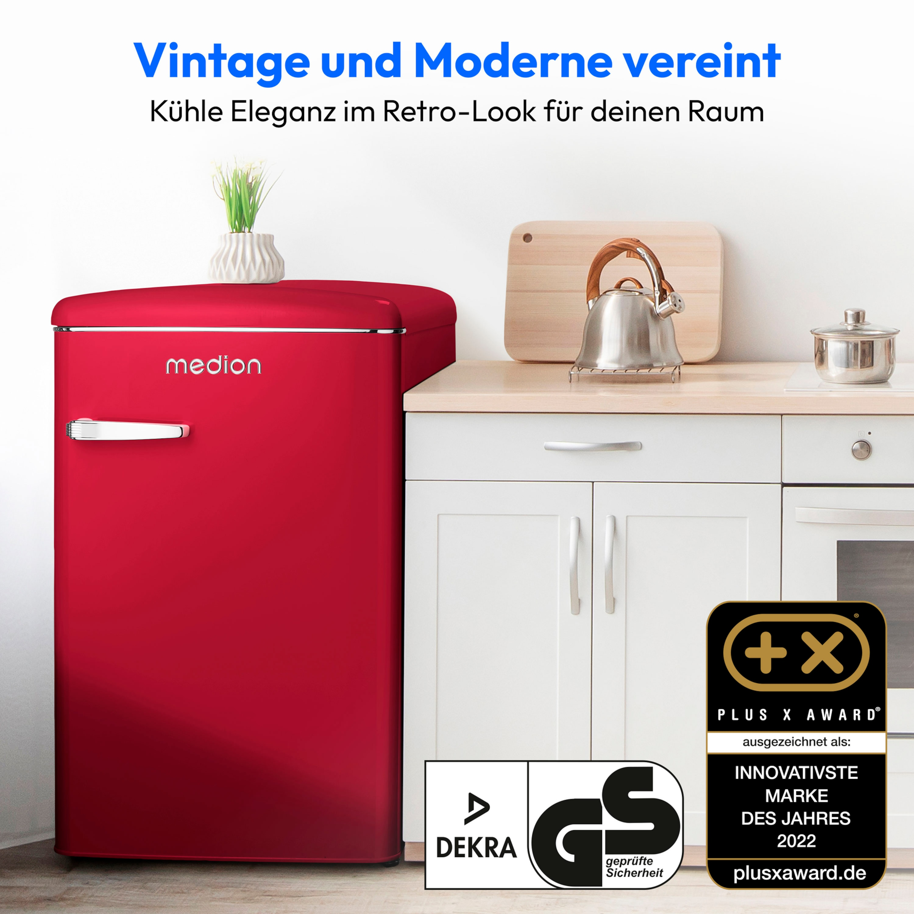 Ein roter Kühlschrank, ein Wasserkocher, ein Schneidebrett und ein Abzeichen in einer weißen Küche.