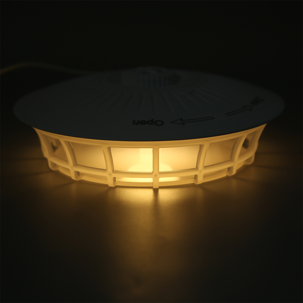 Eine beleuchtete, weiße Lampe mit käfigartigem Design und dem Wort 'open'.
