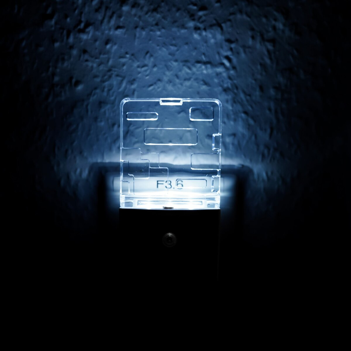 Ein leuchtendes, klares Nachtlicht aus Kunststoff mit dem Text 'F3.6' darauf. Dahinter ist eine dunkle Wand.