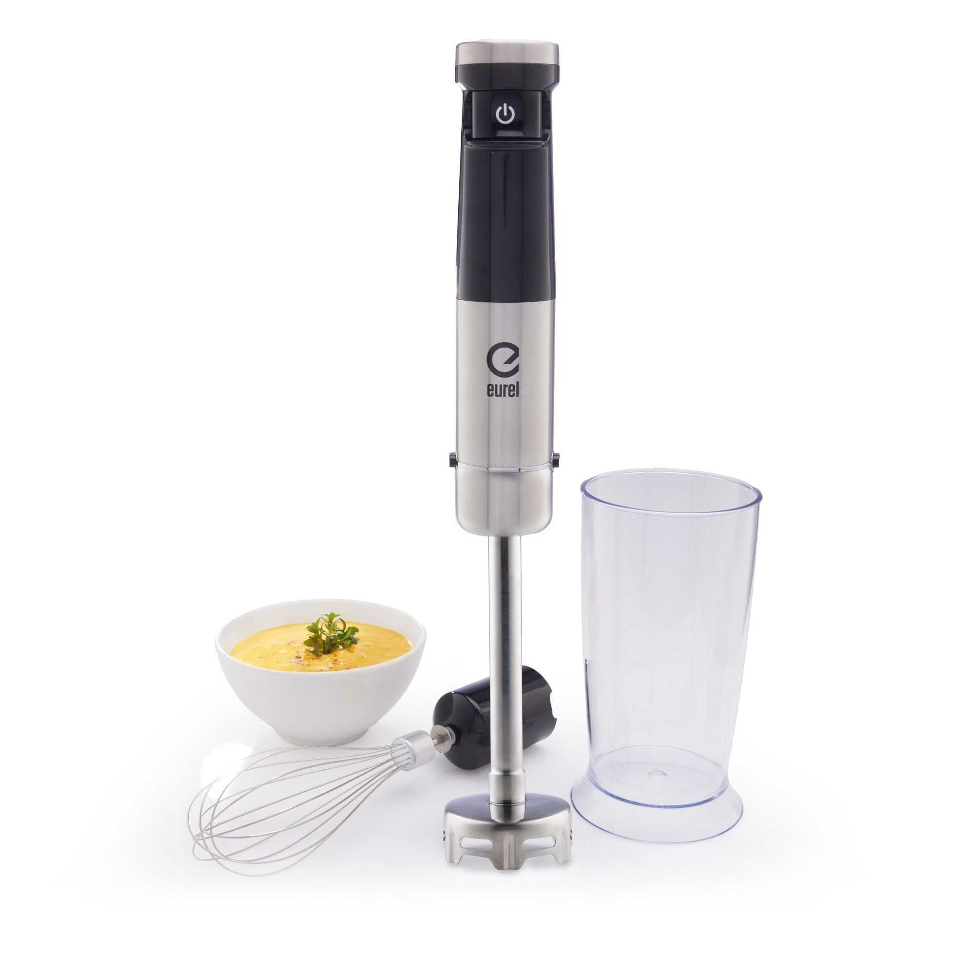 Stabmixer, Schüssel mit Suppe, Schneebesen und Messbecher auf Weiß.