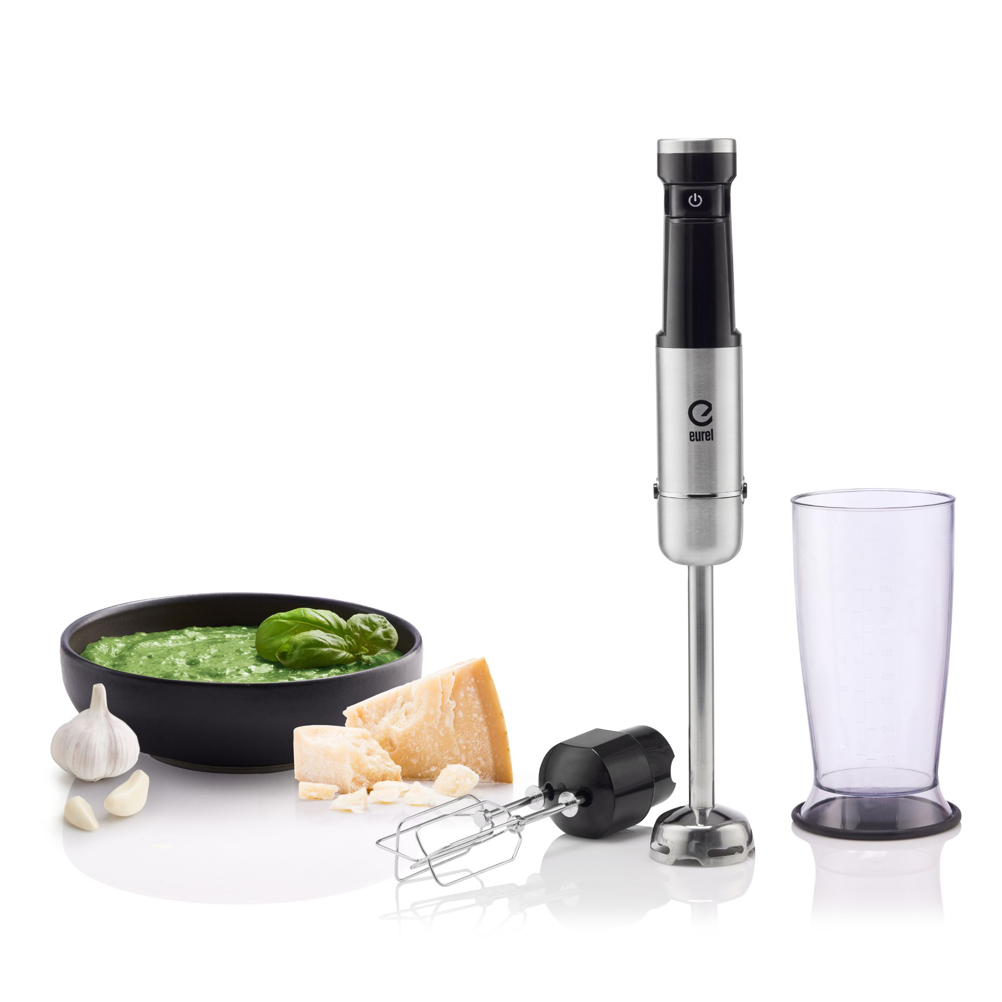 Silberner Stabmixer mit Zubehör, Schüssel mit Pesto, Parmesan, Knoblauch, weißer Hintergrund.