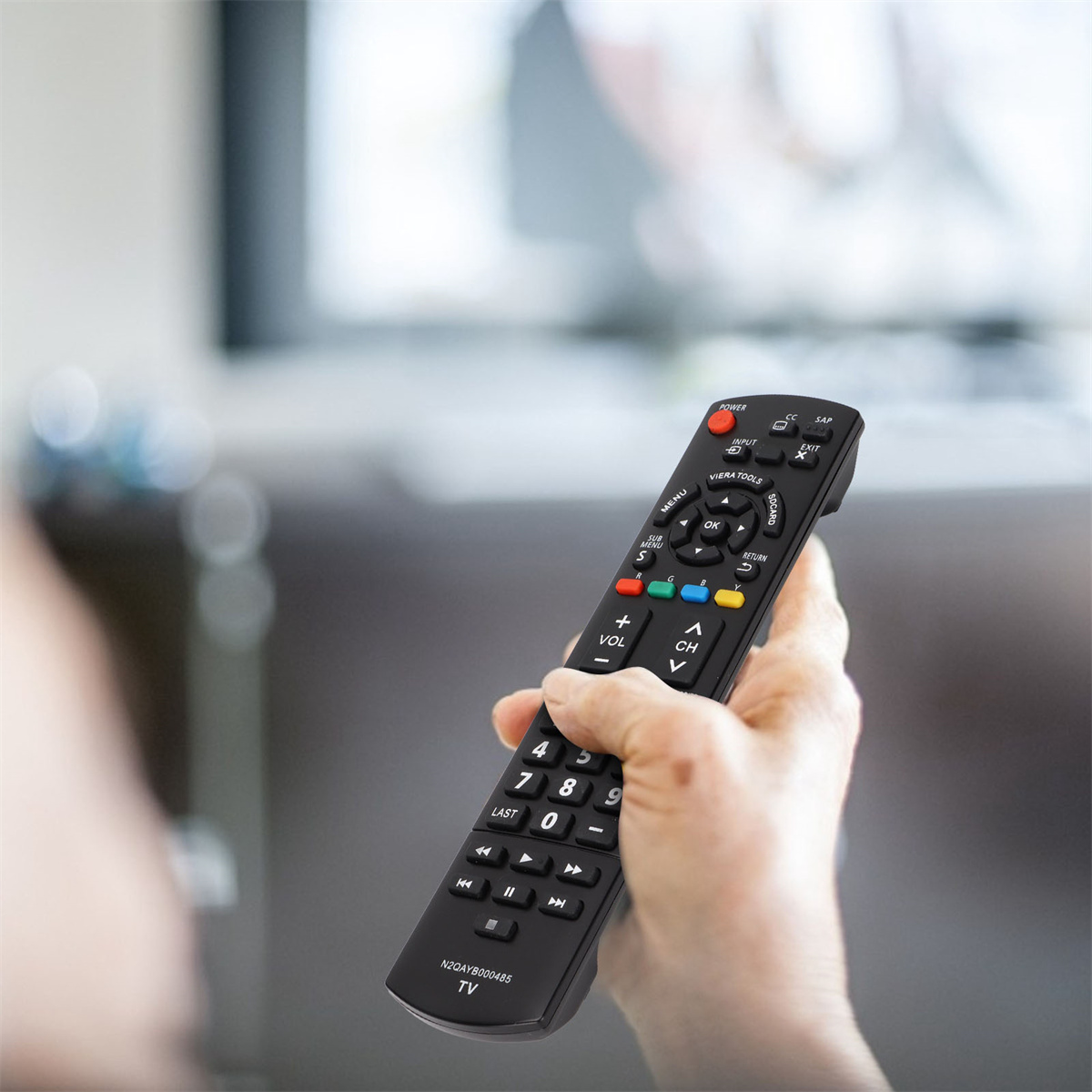Hand hält schwarze TV-Fernbedienung mit mehreren Knöpfen, Fokus auf Knöpfe.