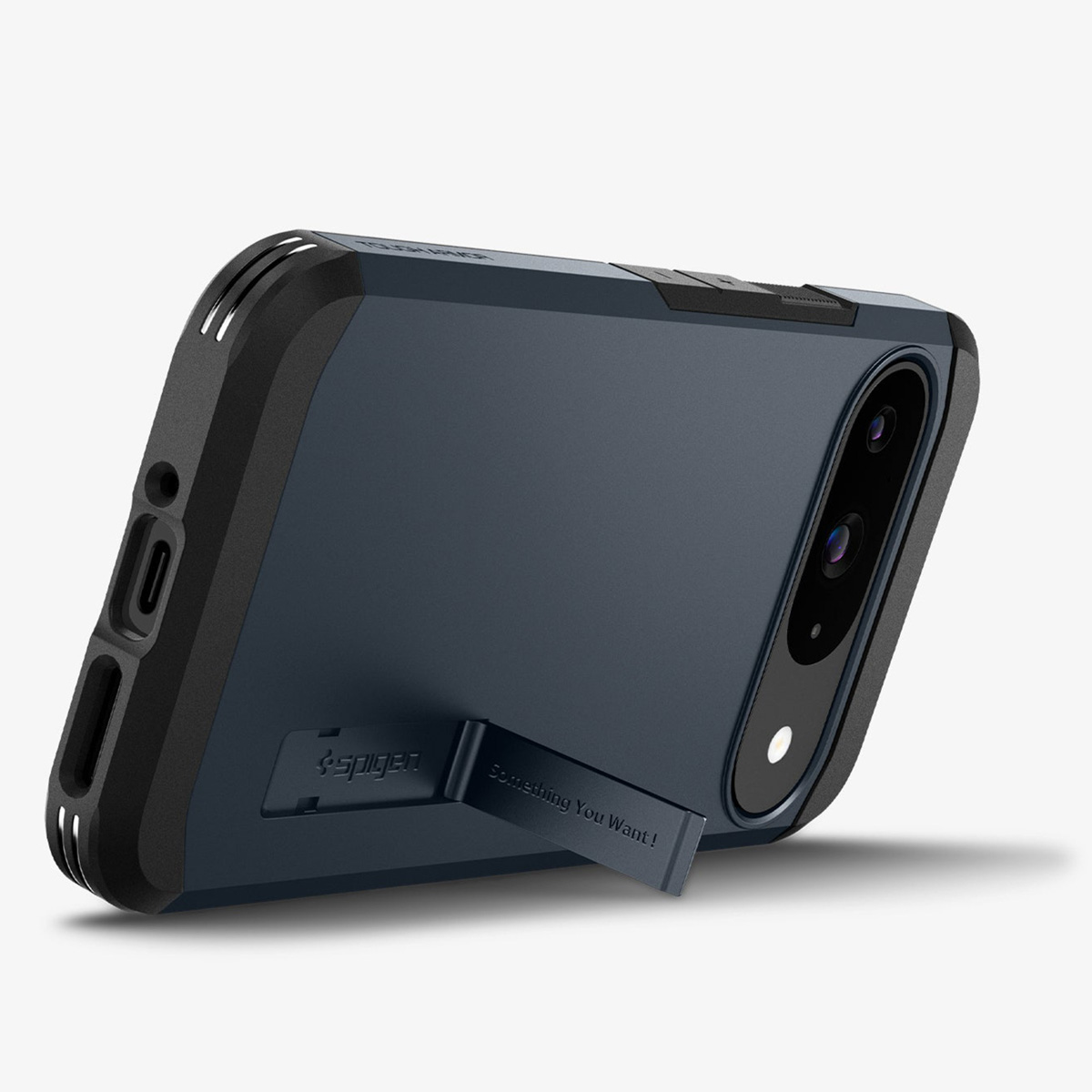 Ein Telefon in einer dunkelblauen Hülle, abgewinkelt mit einem Ständer. Auf dem Ständer steht „Spigen“ und „Something You Want!"