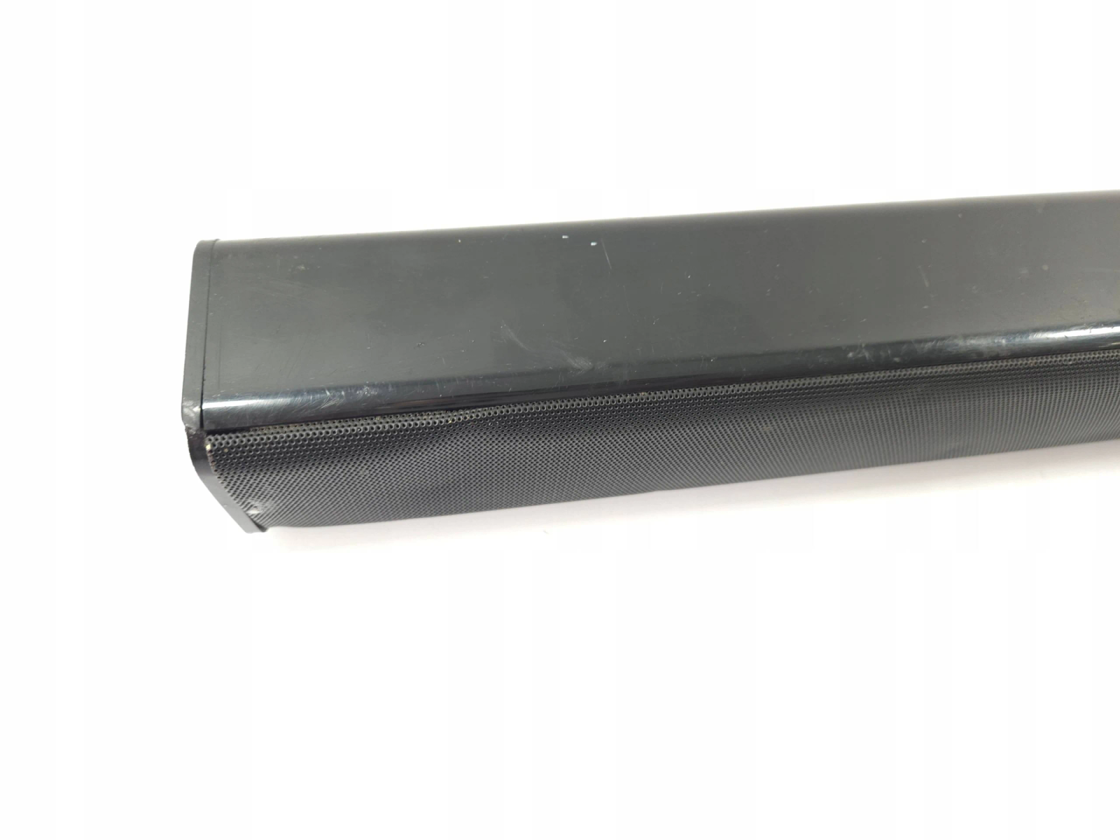 Una soundbar nera lunga su una superficie bianca. La parte anteriore ha una rete che copre gli altoparlanti.