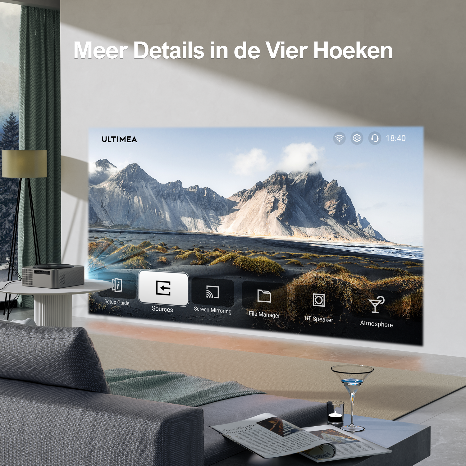 A projector displays a mountain landscape scene. A couch, table with a drink, and a lamp are in the foreground. Text says 'Meer Details'.