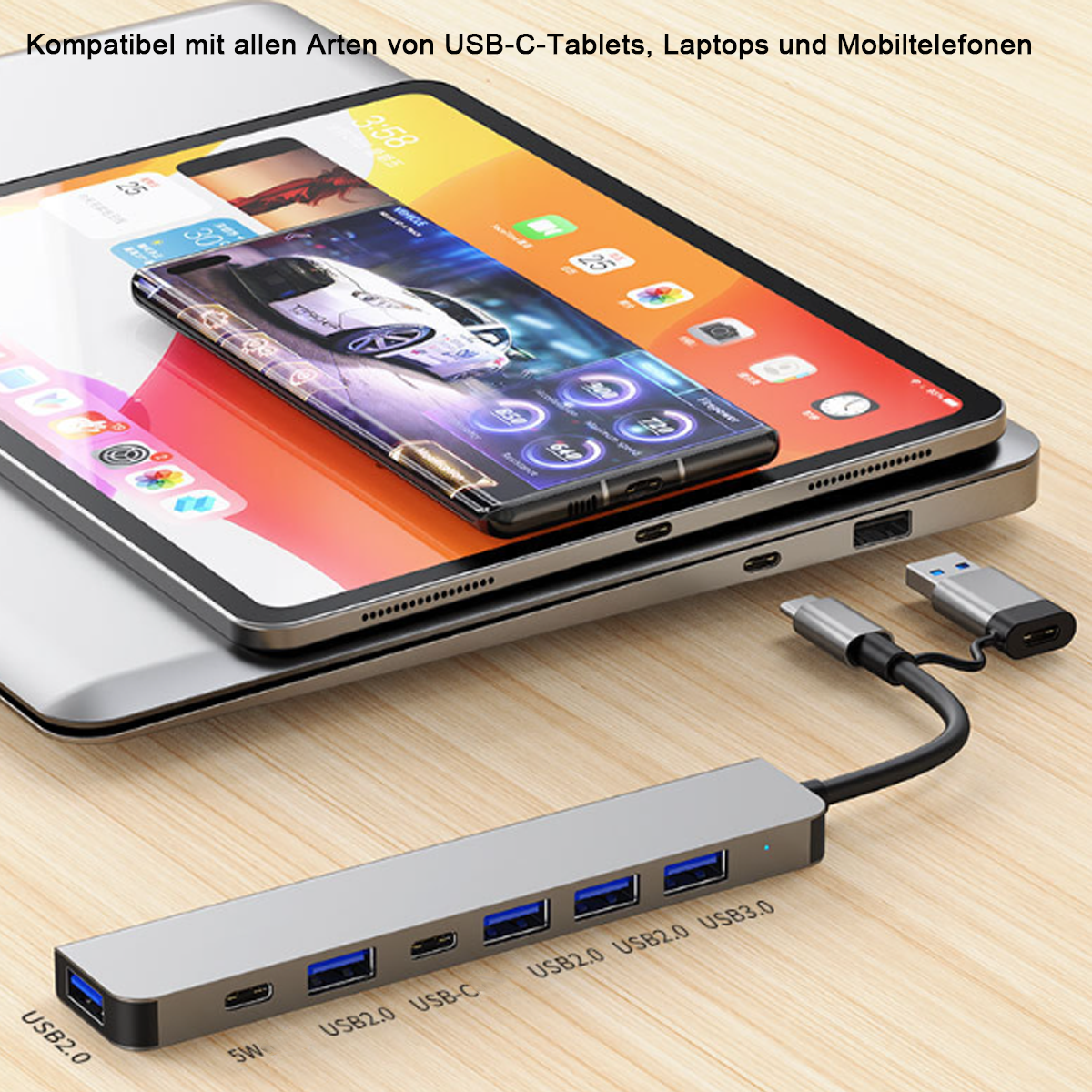 Ein silberner USB-Hub mit mehreren Anschlüssen ist mit einem Tablet und einem Smartphone verbunden. Die Geräte liegen auf einem Holztisch.