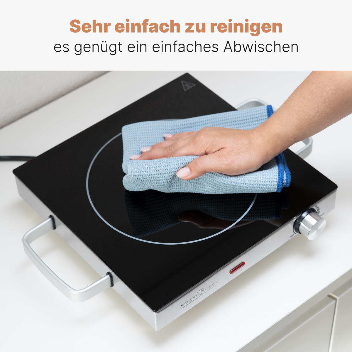 Dłoń obracająca pokrętło na srebrnym urządzeniu.