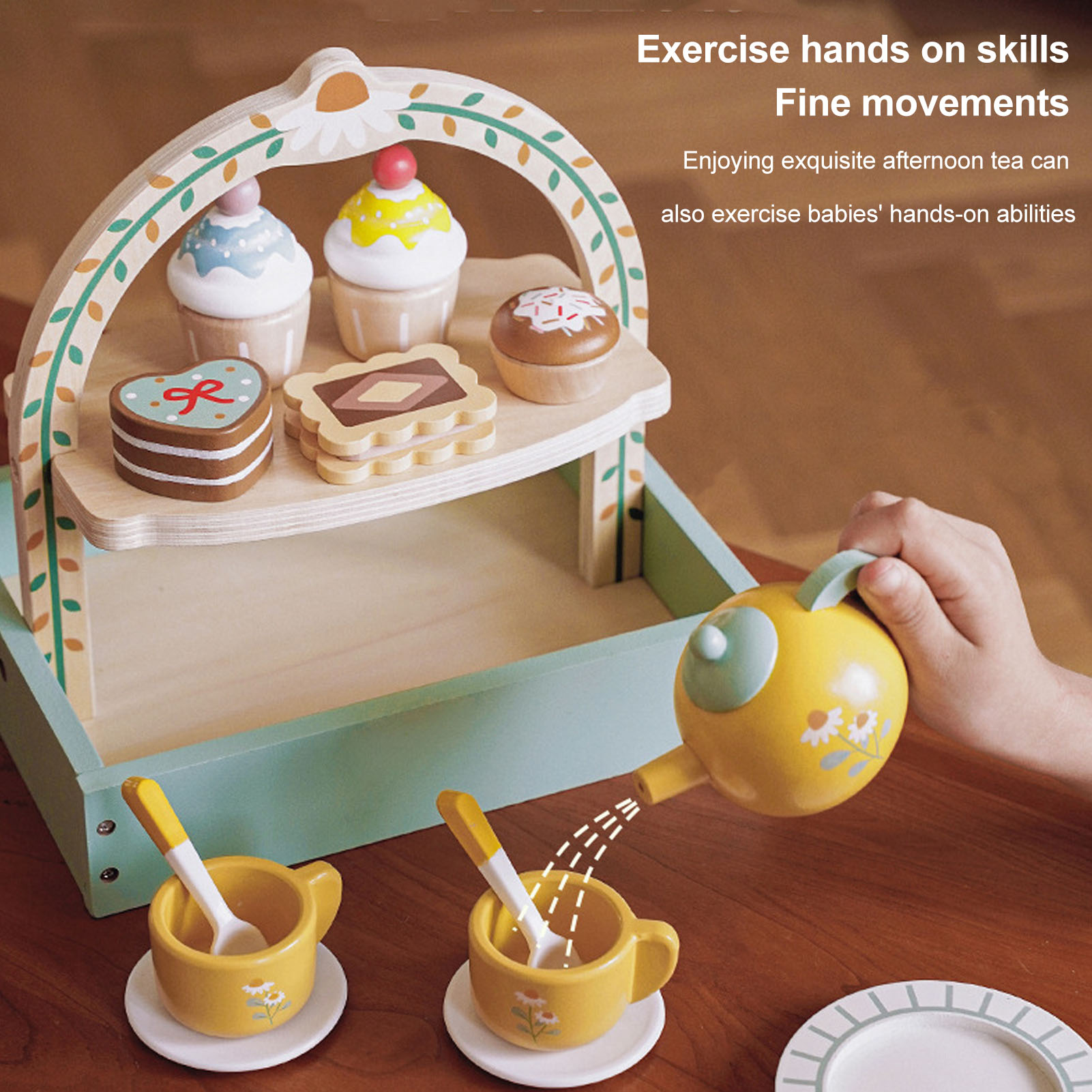 Holzspielzeugset mit Cupcakes, Keksen und einer Teekanne. Eine Kinderhand gießt Wasser in Tassen.