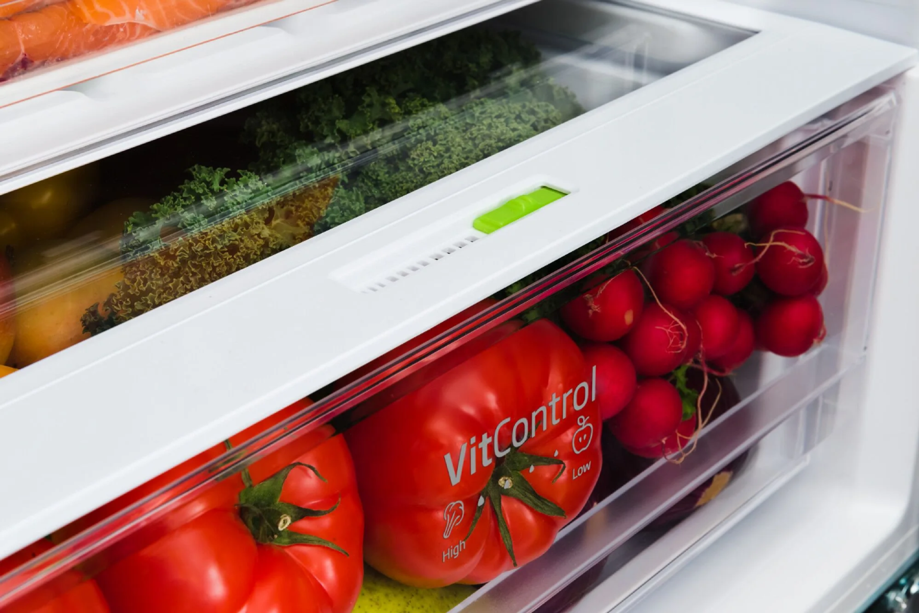 Szuflada lodówki z warzywami i pomidorami, zbliżenie. Białe tło.