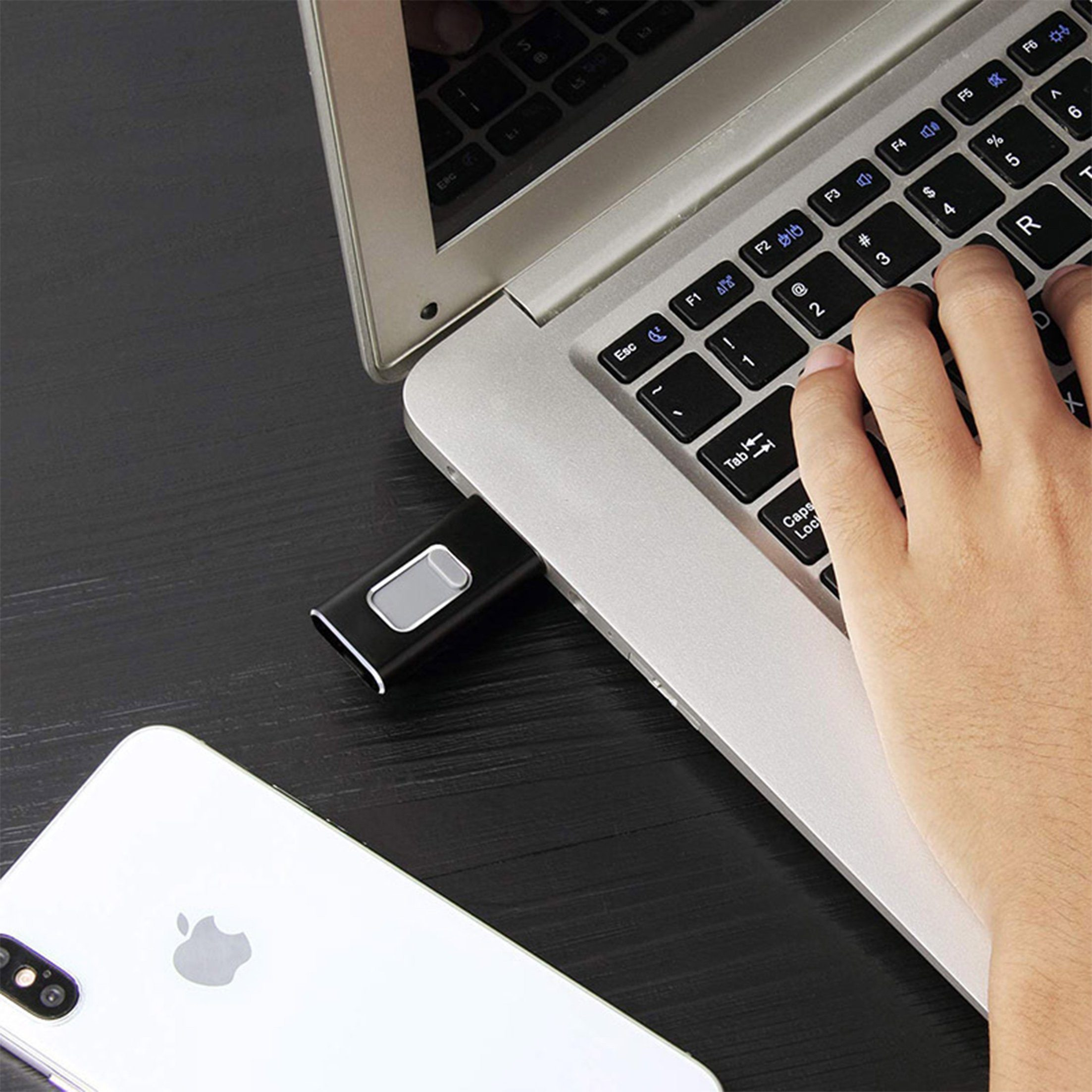 Eine Hand tippt auf der Laptop-Tastatur, mit einem eingesteckten USB-Laufwerk.