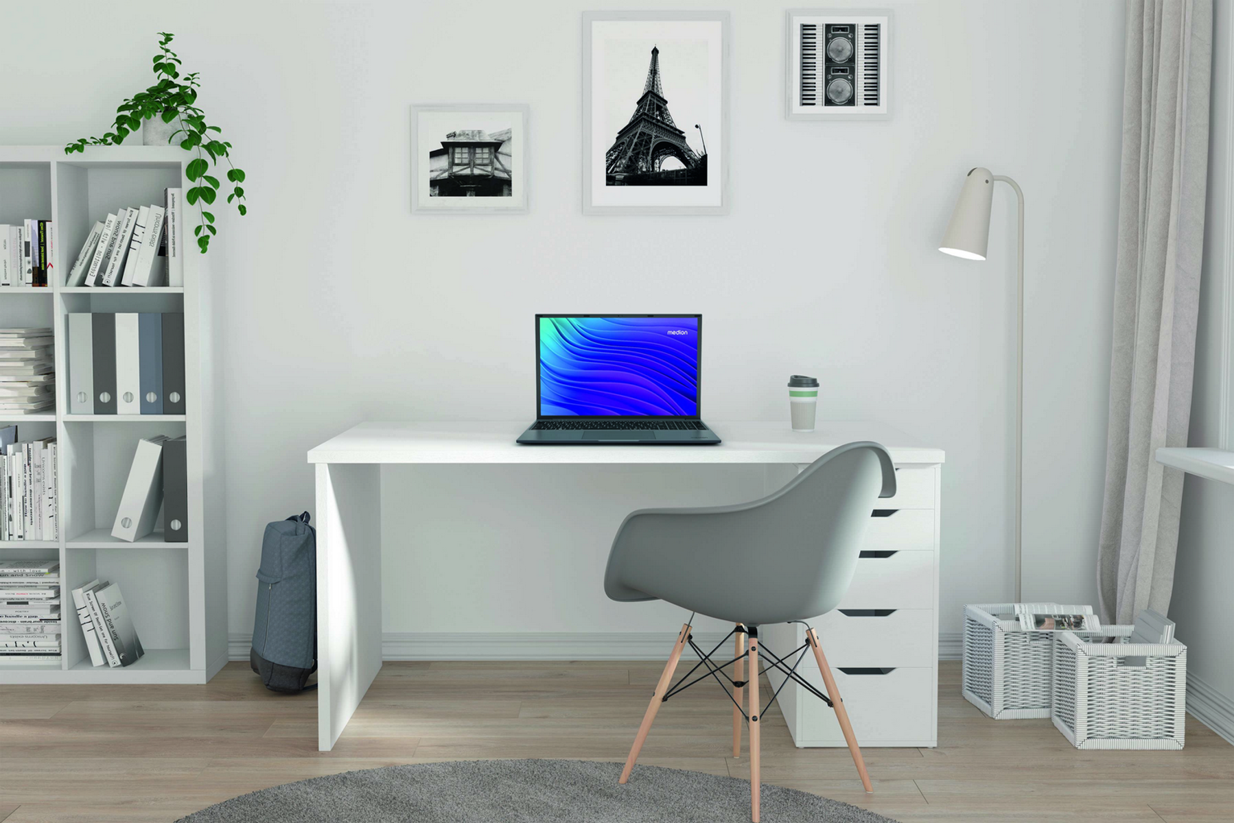 Escritorio blanco con portátil, silla y decoración. Obras de arte en la pared. Estantería a la izquierda. Ventanas a la derecha.