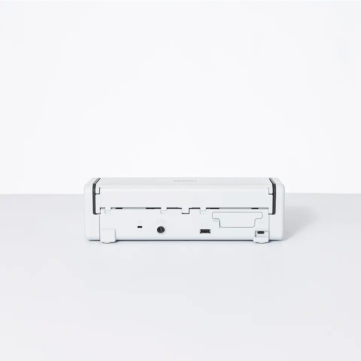 Mała biała drukarka, widok z przodu, z portami i wejściem zasilania.