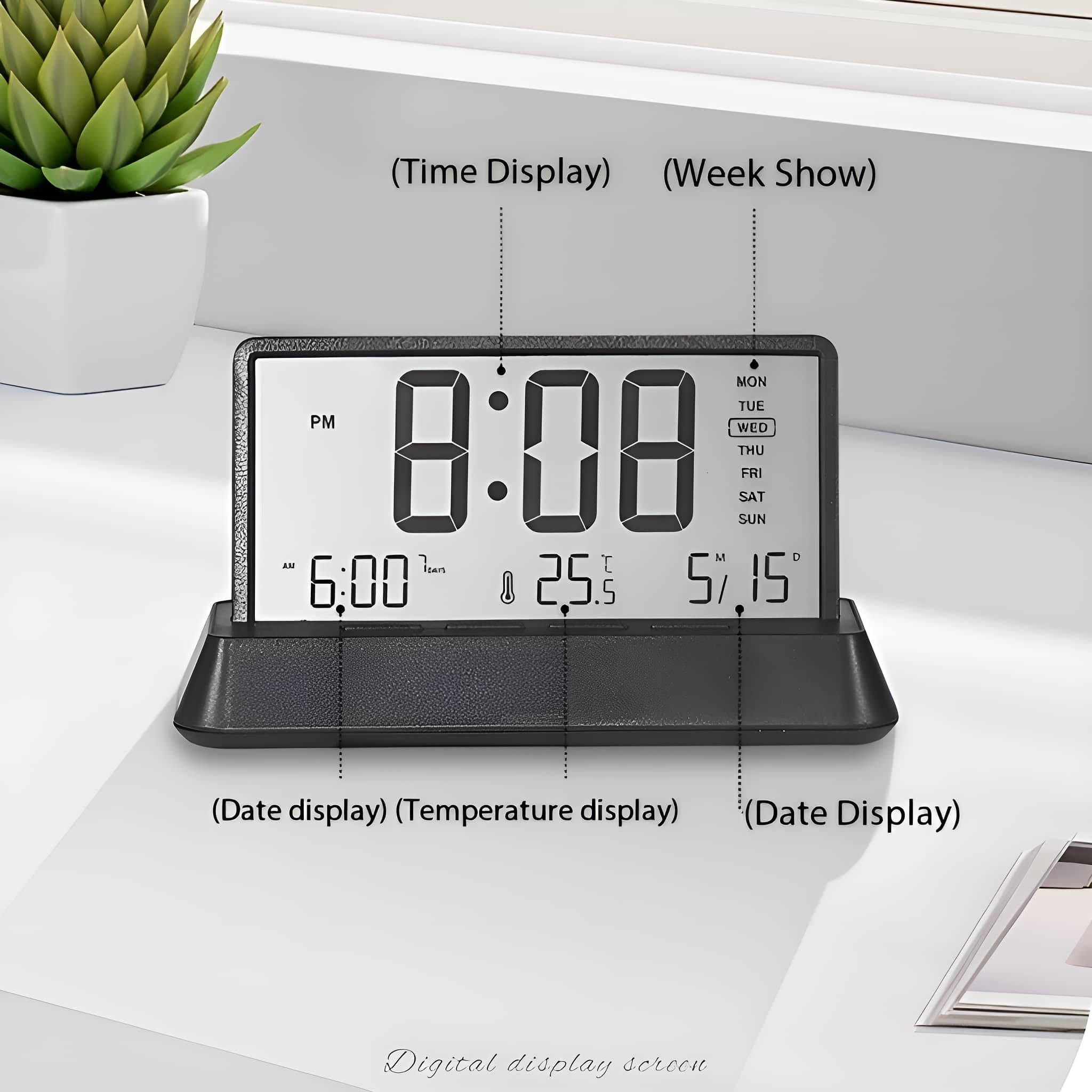 Schwarze Digitaluhr, die Zeit, Datum und Temperatur anzeigt. Sie steht auf einer weißen Oberfläche neben einer Pflanze.