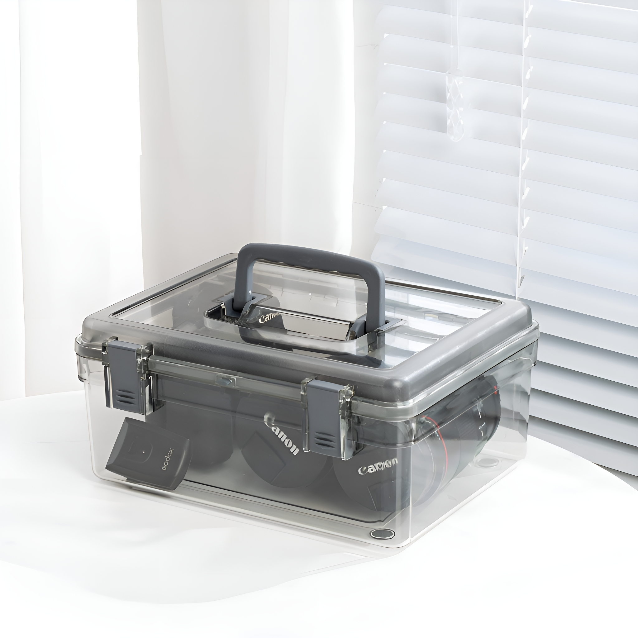 Transparente Plastikbox mit grauem Griff und Verschlüssen. Enthält Kameras und Zubehör. Weißer Hintergrund.