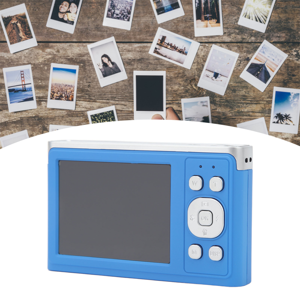 Blaue Kamera mit Bildschirm. Polaroids auf Holzgrund darüber. Eine Hand hält eins.