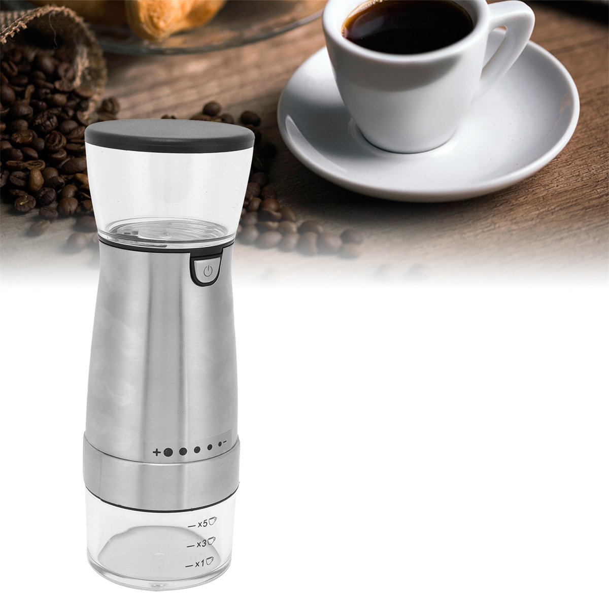 Kaffeemühle aus Edelstahl. Eine Tasse Kaffee und Bohnen liegen daneben.