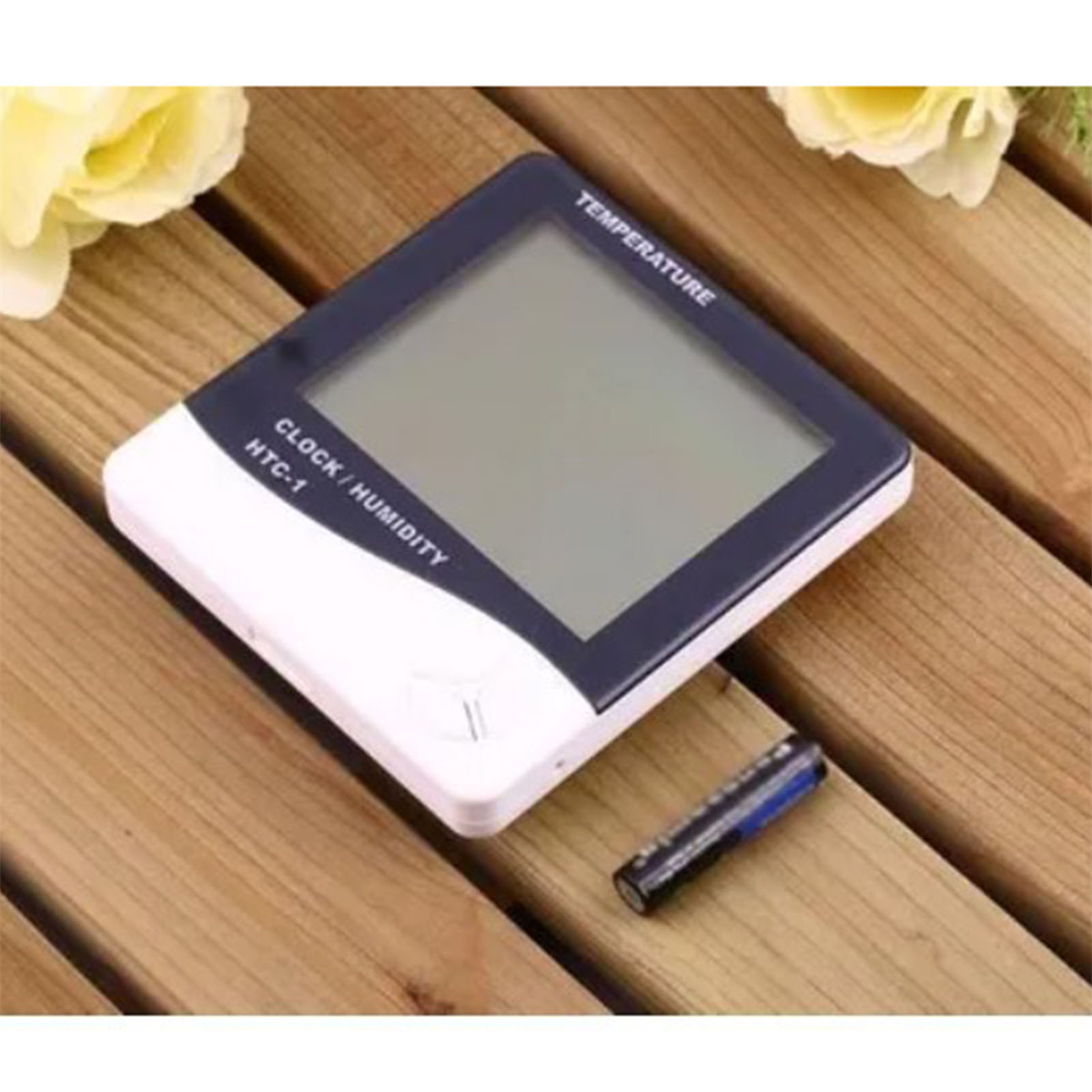 Digitales Thermometer mit Batterie auf Holzoberfläche.