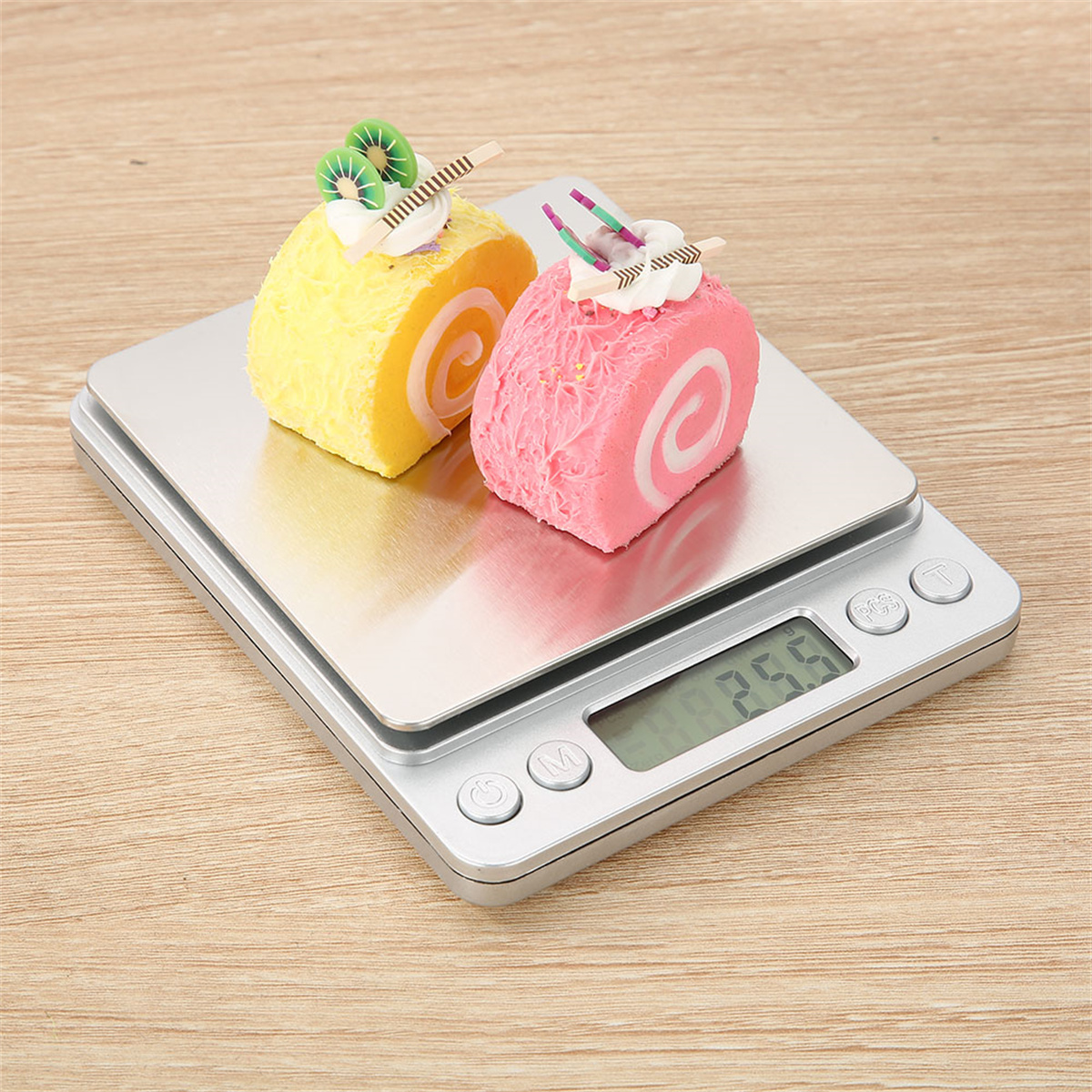 Zwei kleine, dekorierte Kuchen auf einer Digitalwaage. Die Waage zeigt 2,55. Holztisch.