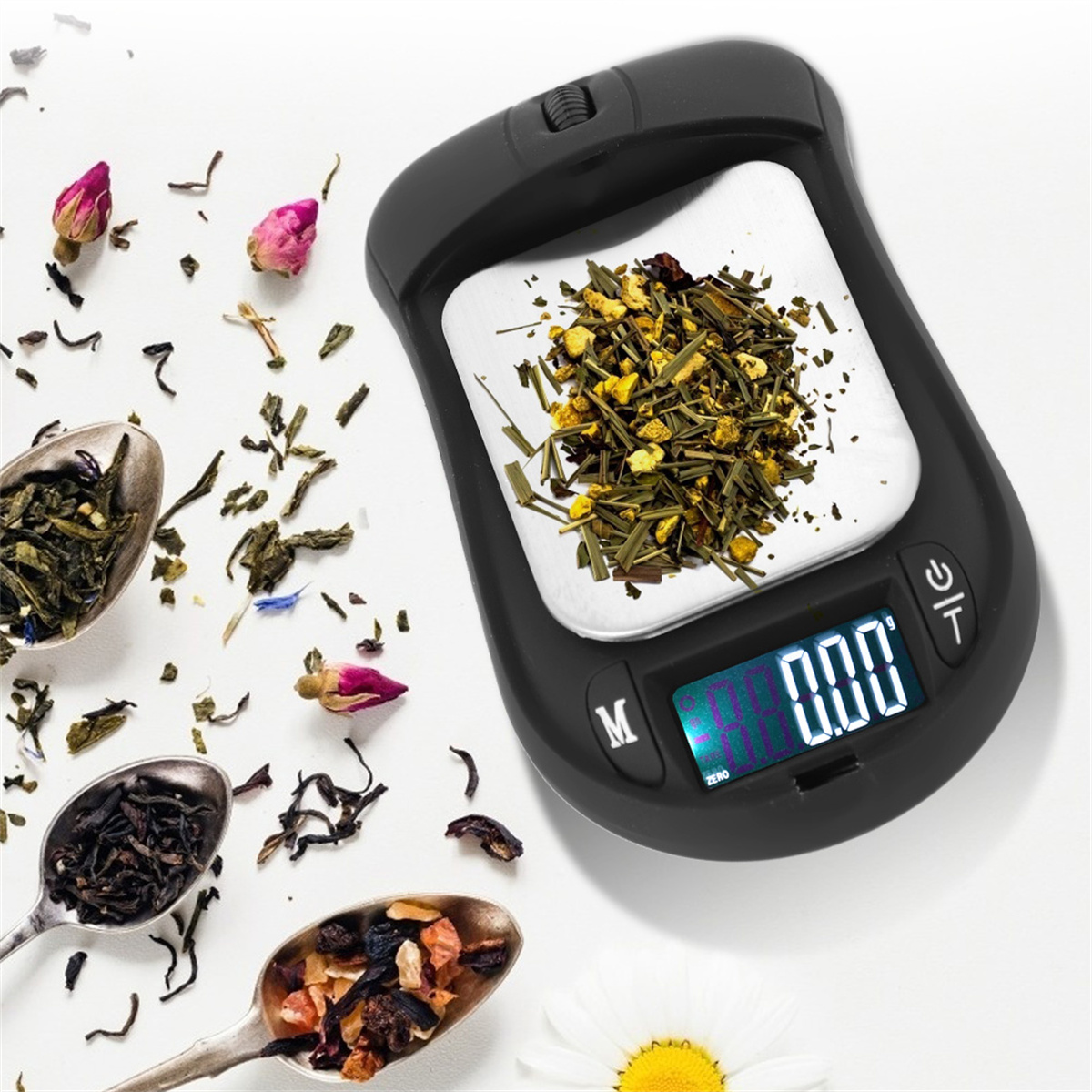 Schwarze Digitalwaage mit Teeblättern und Blumen darauf. Löffel mit Teeblättern und Blumen um die Waage herum.