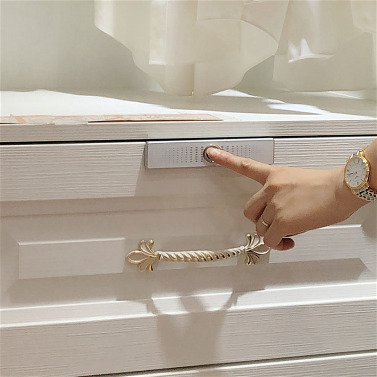 Ein Finger berührt einen Schubladenöffnungs-Knopf an einem weißen Schrank.