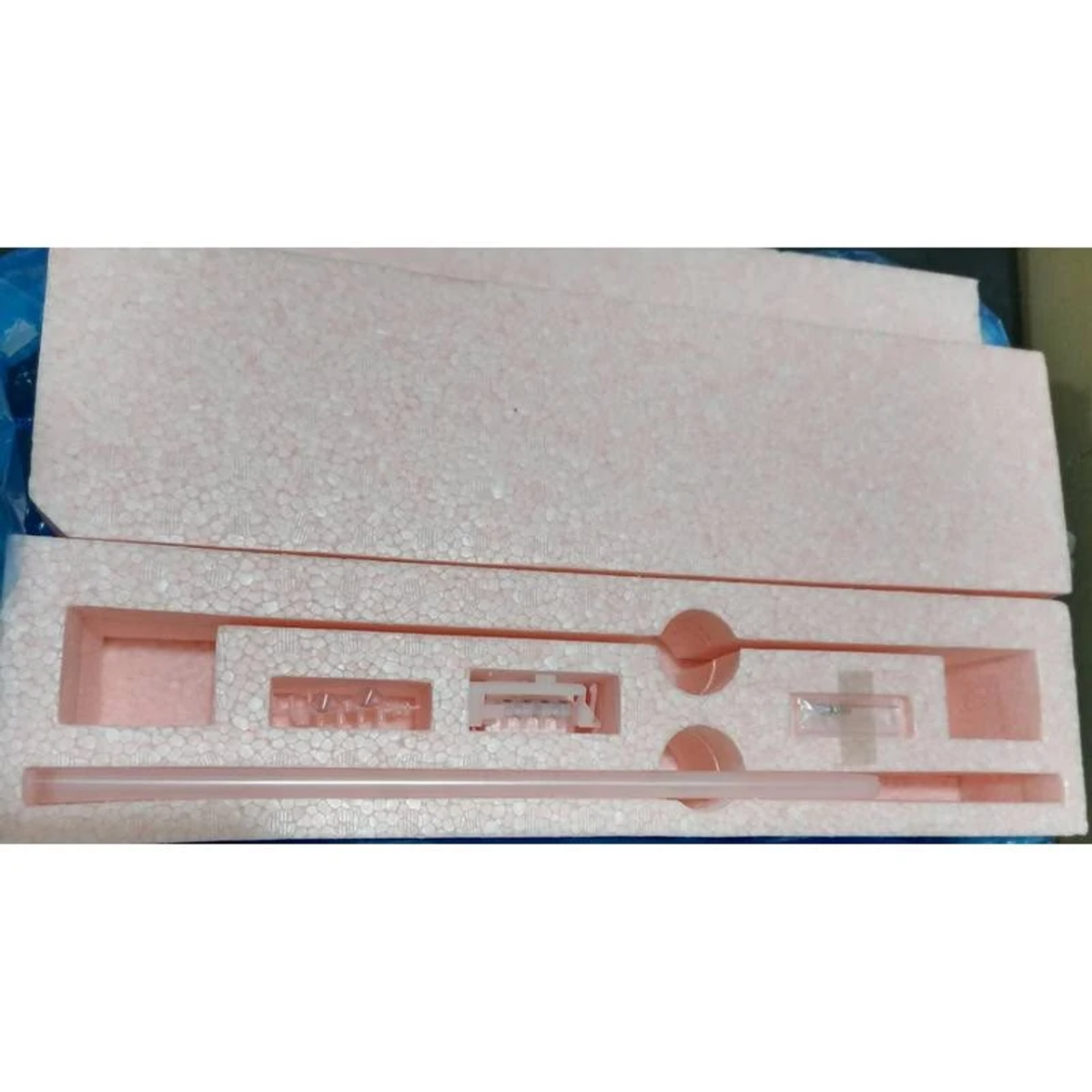 Embalaje de espuma rosa con recortes para piezas. Algunas piezas son visibles dentro.