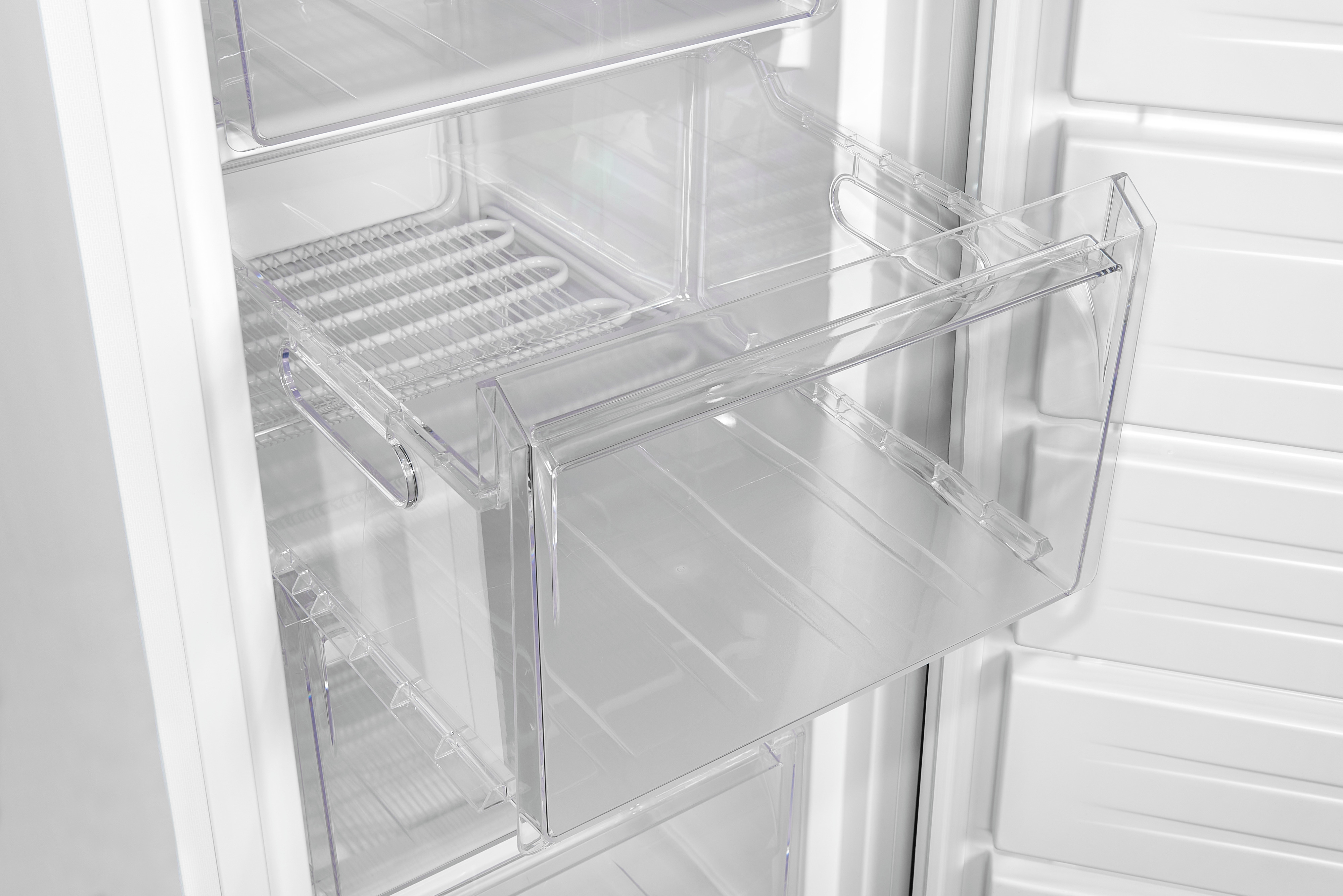 Interior de un refrigerador, mostrando cajones y estantes de plástico transparente.