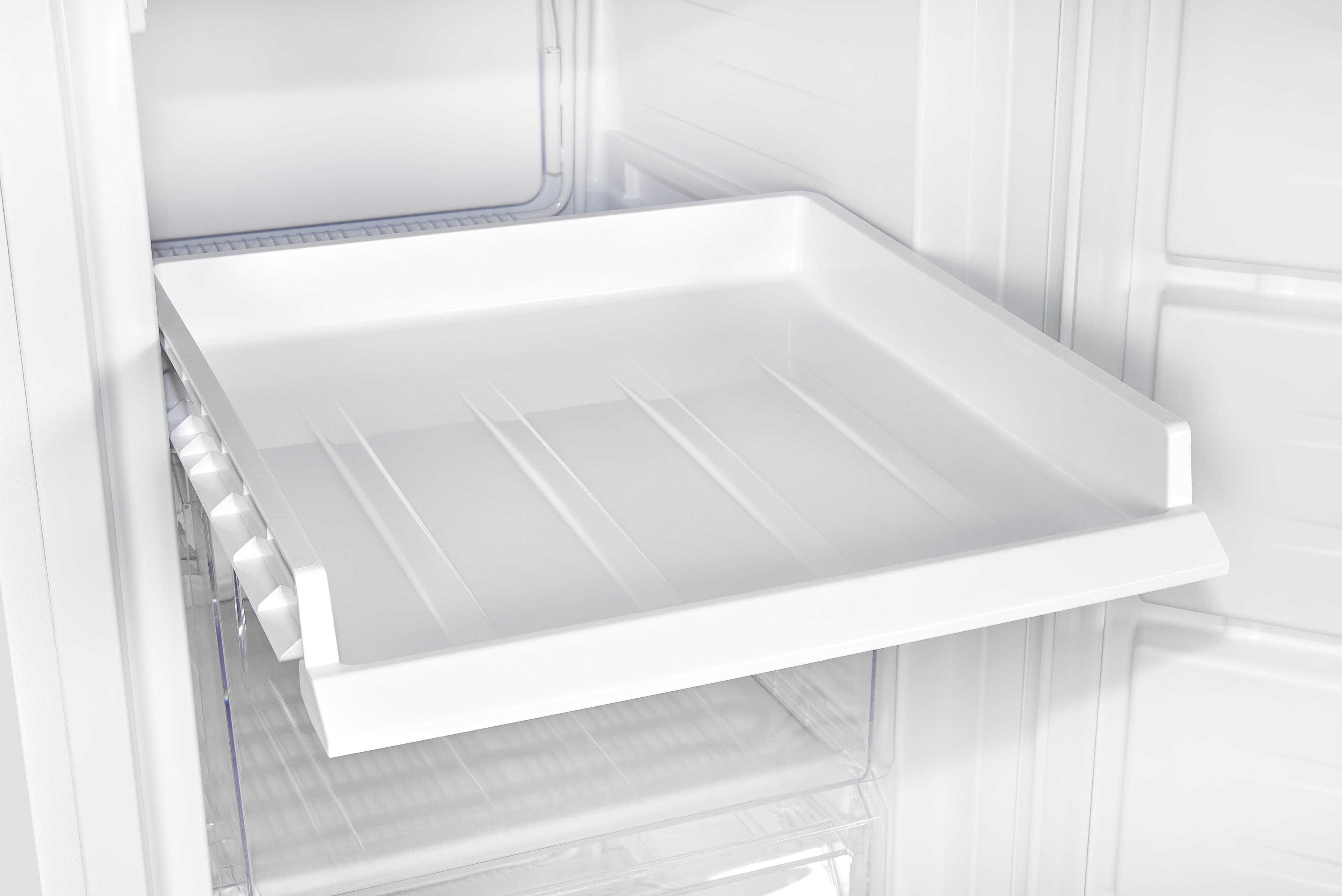 Interior de nevera blanco con un cajón blanco extraído, vacío, limpio y brillante.