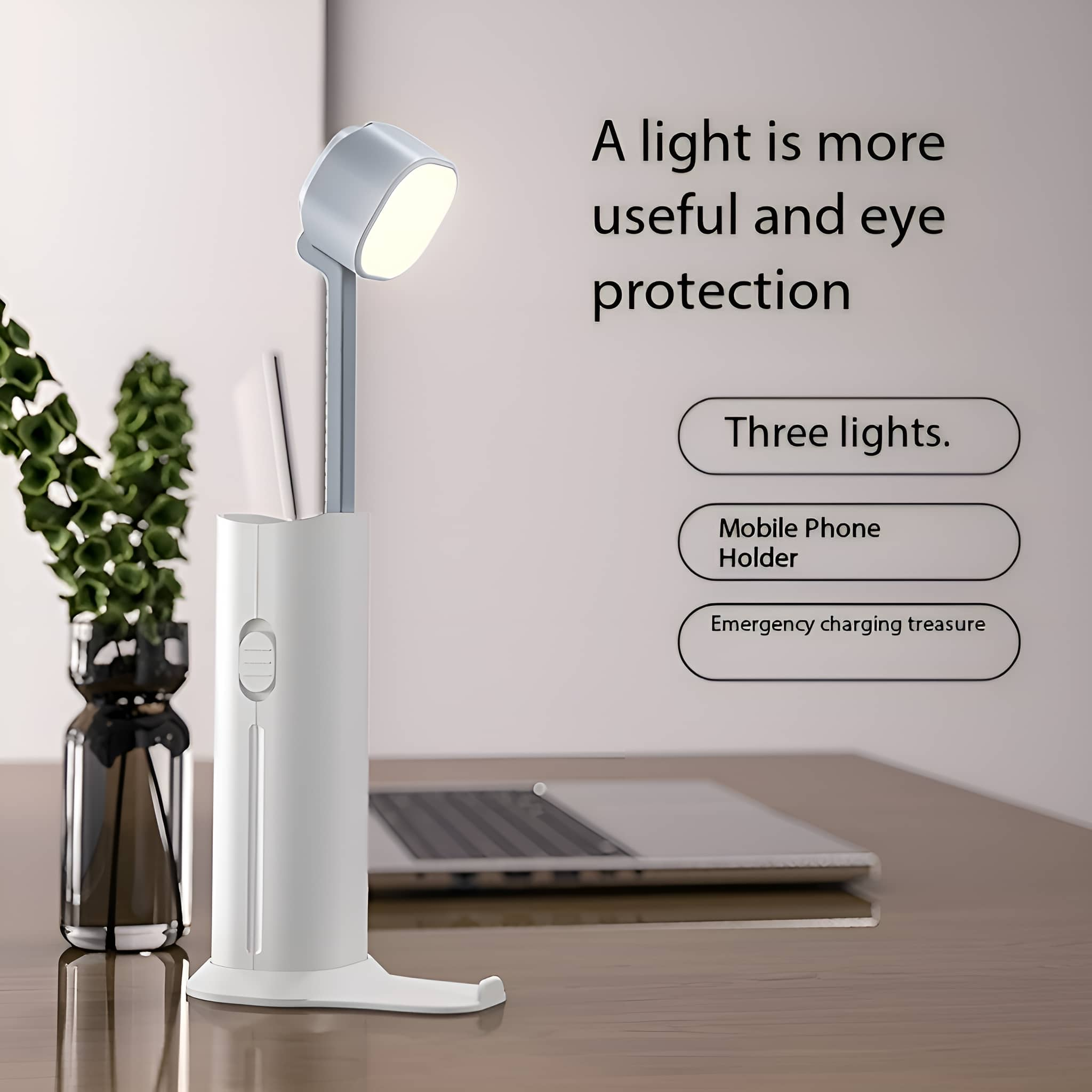 Weiße Schreibtischlampe mit Telefonhalter. Im Hintergrund befinden sich ein Laptop und einige Dekorationsgegenstände.