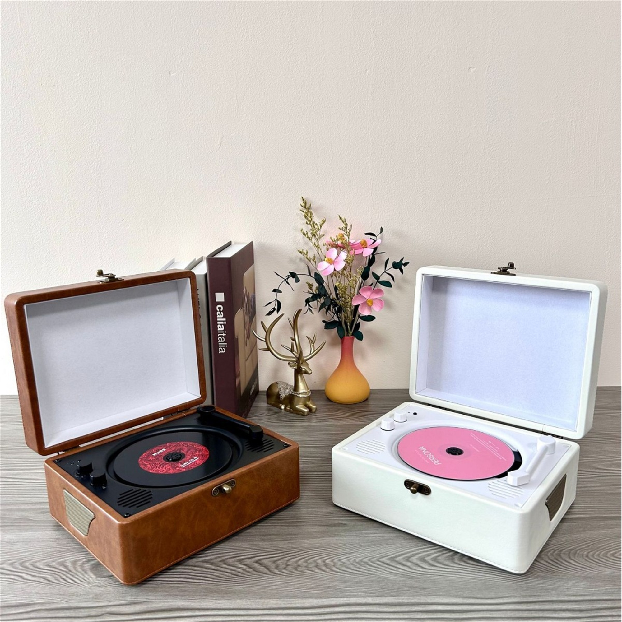 Zwei Vintage-Plattenspieler, einer braun, einer weiß. Alben und Dekoration im Hintergrund.