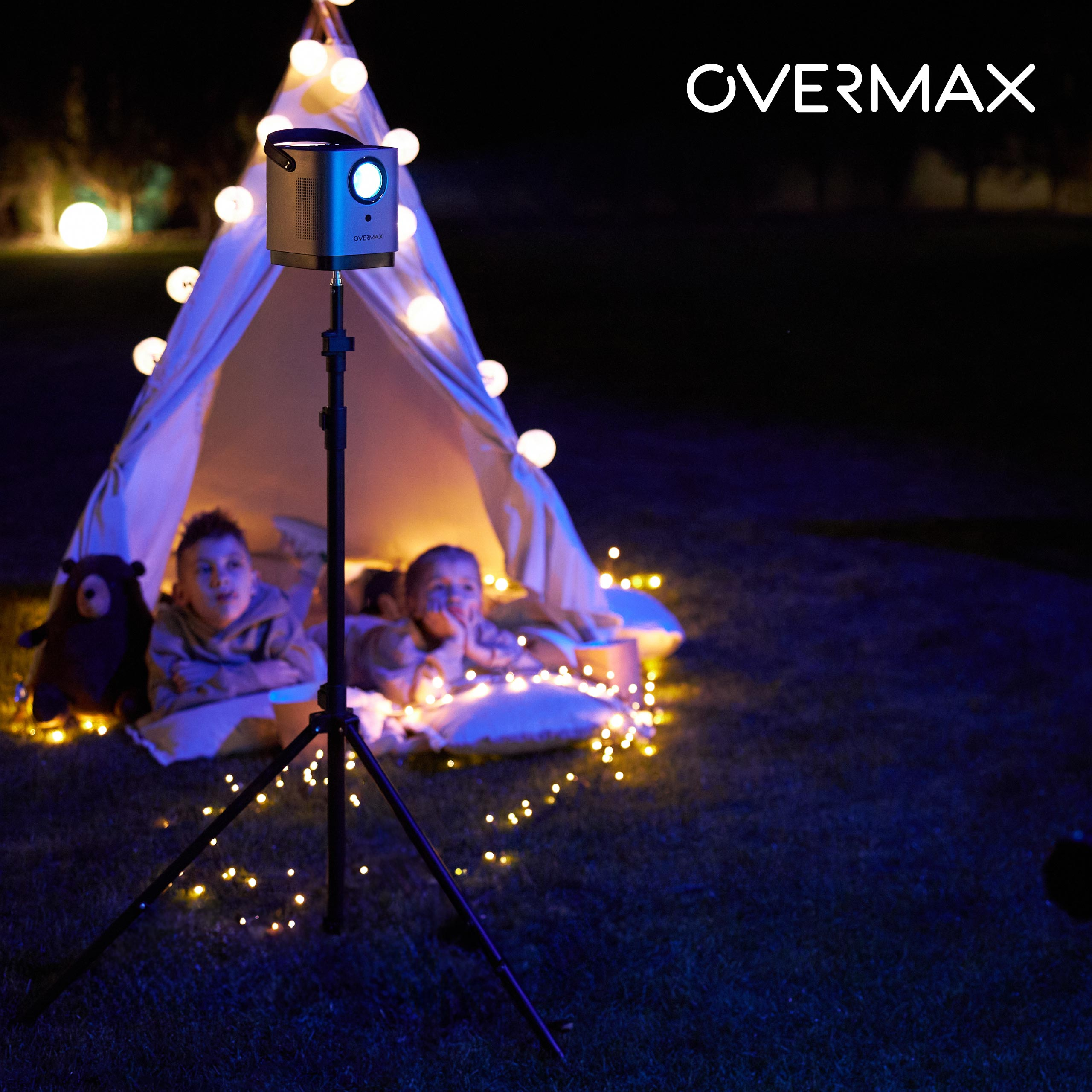 Konfiguracja projektora z namiotem i dwójką dzieci oglądających. Widoczne światła i logo OVERMAX.