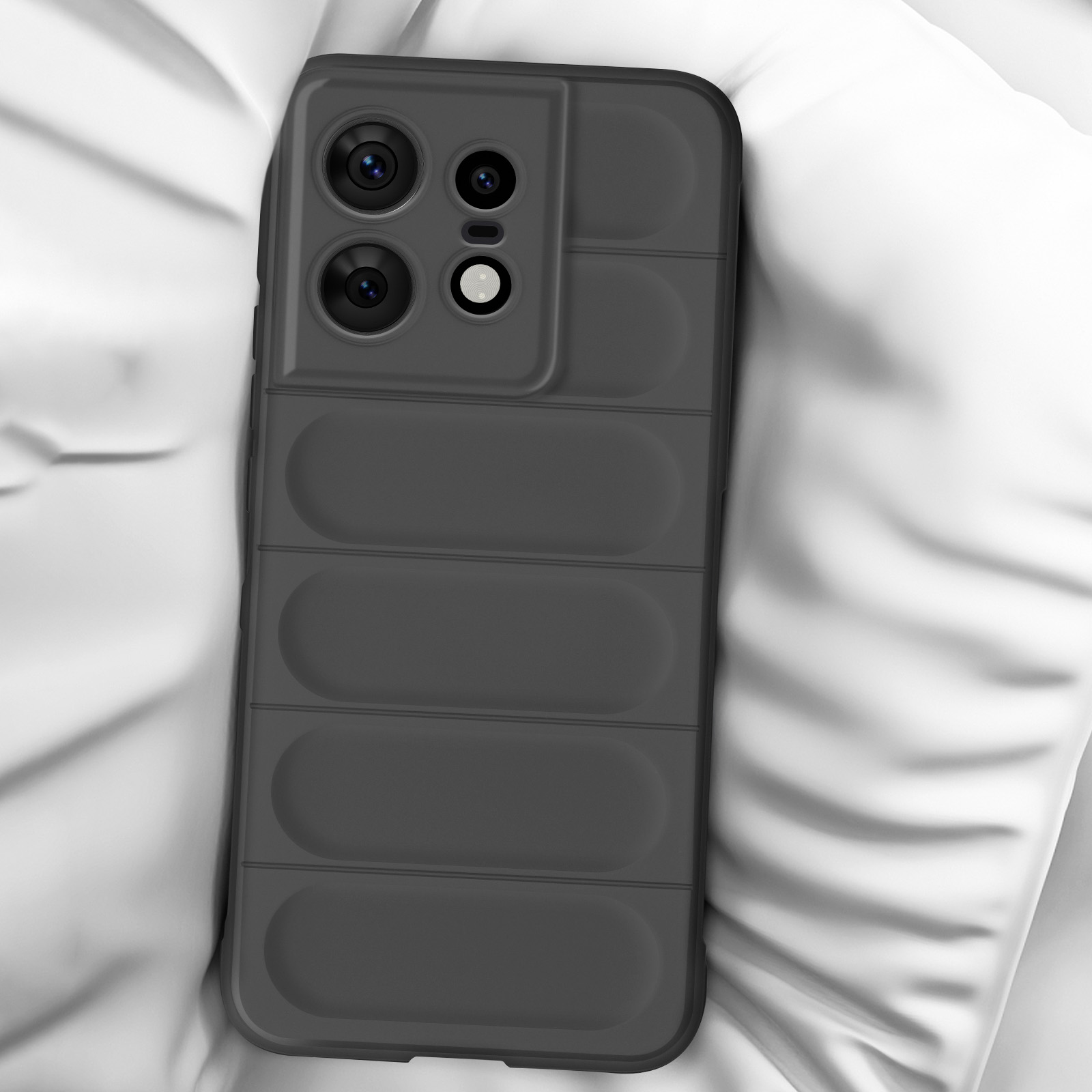 Une coque de téléphone noire avec une bosse pour la caméra sur un lit blanc. La coque a un design rectangulaire.