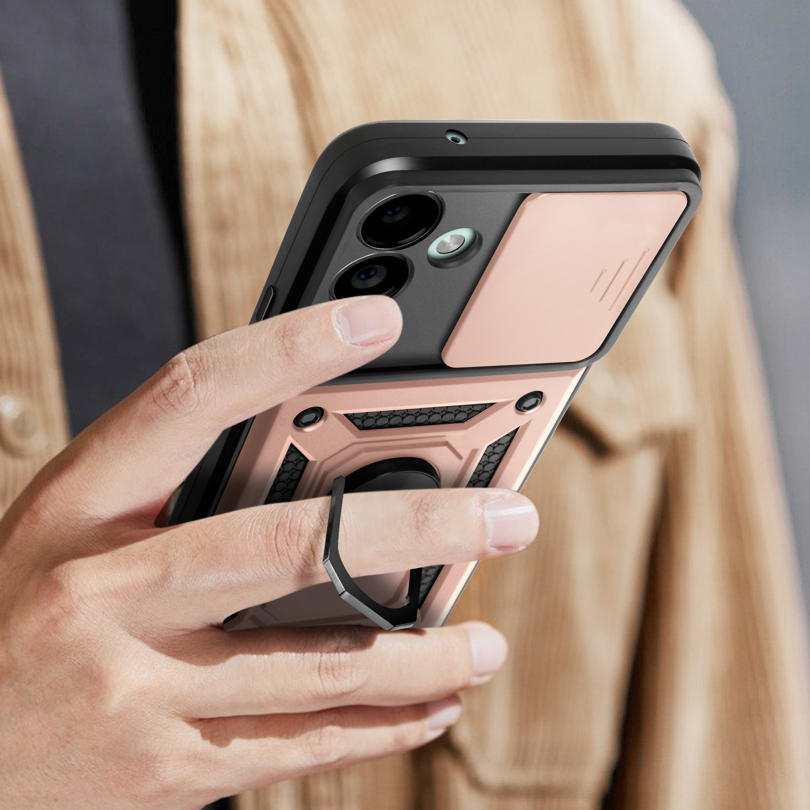 Smartphone in una custodia con anello di supporto. Tenuto in mano, dettagli oro rosa e neri. Sfondo beige.
