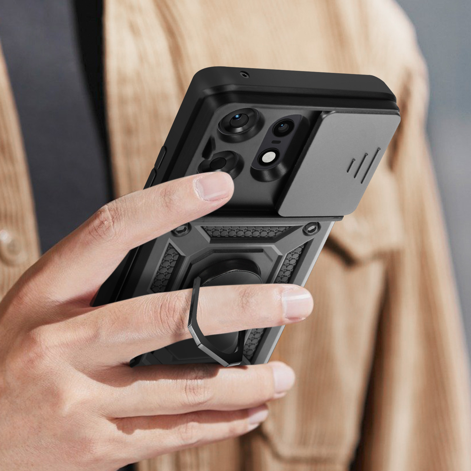 Custodia per telefono nera con anello. Il dito tiene l'anello. La parte posteriore ha un ritaglio per la fotocamera e un design.