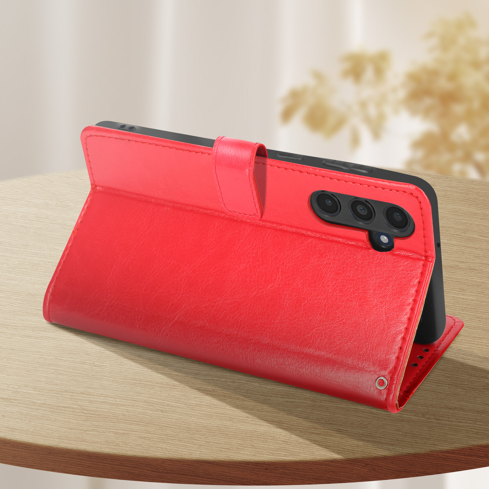 Rote Handyhülle auf Holzoberfläche, geöffnet, um das Handy zu zeigen. Das Handy hat drei Kameras.