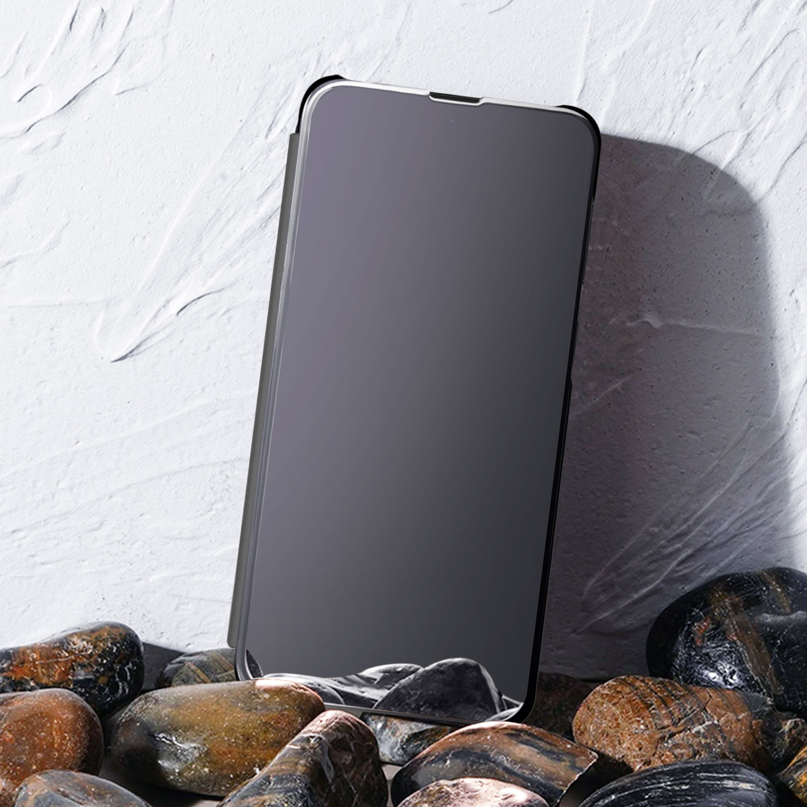 Telefono in una custodia, appoggiato su rocce. La custodia è grigio scuro e riflettente.