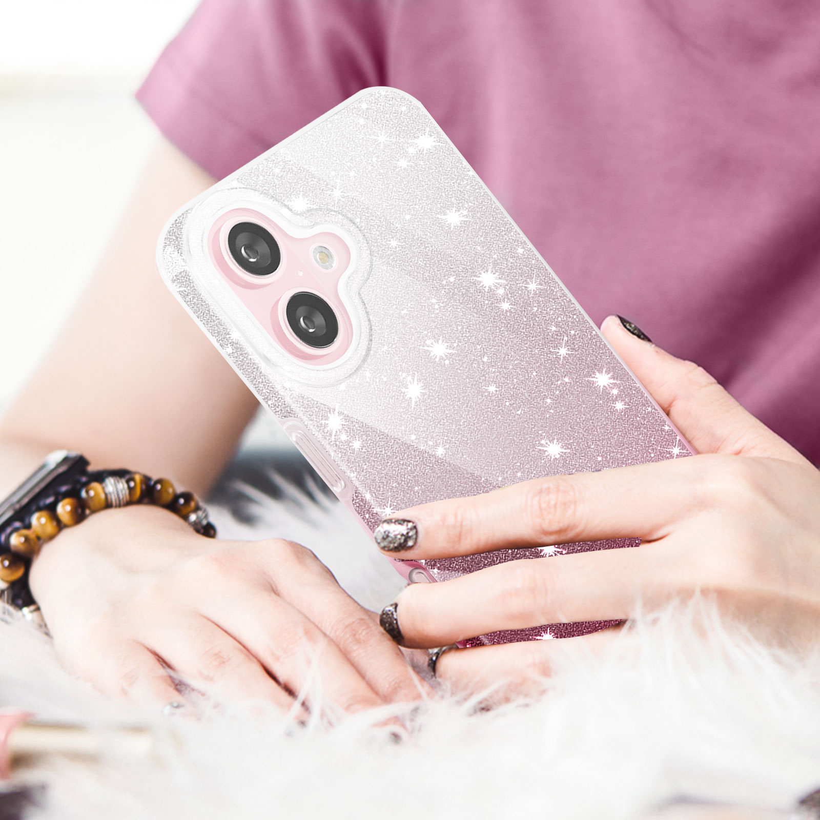 Una donna che tiene una custodia per telefono con glitter e un gradiente rosa. Le sue unghie sono nere.
