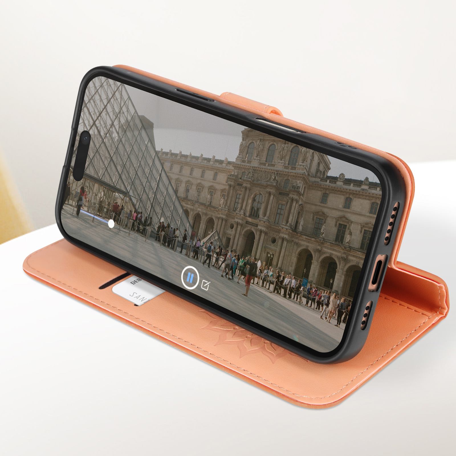 Un telefono in una custodia arancione che mostra un video di un edificio con persone davanti.