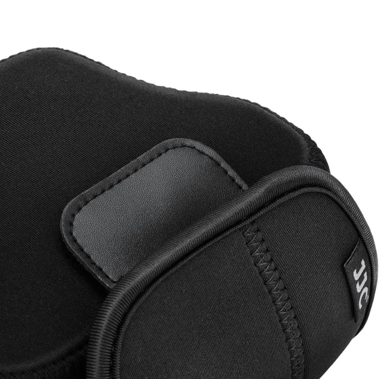 Schwarze Objektivabdeckung aus Neopren. Zeigt die Klappe und die Nahtdetails auf einer gekrümmten Oberfläche.