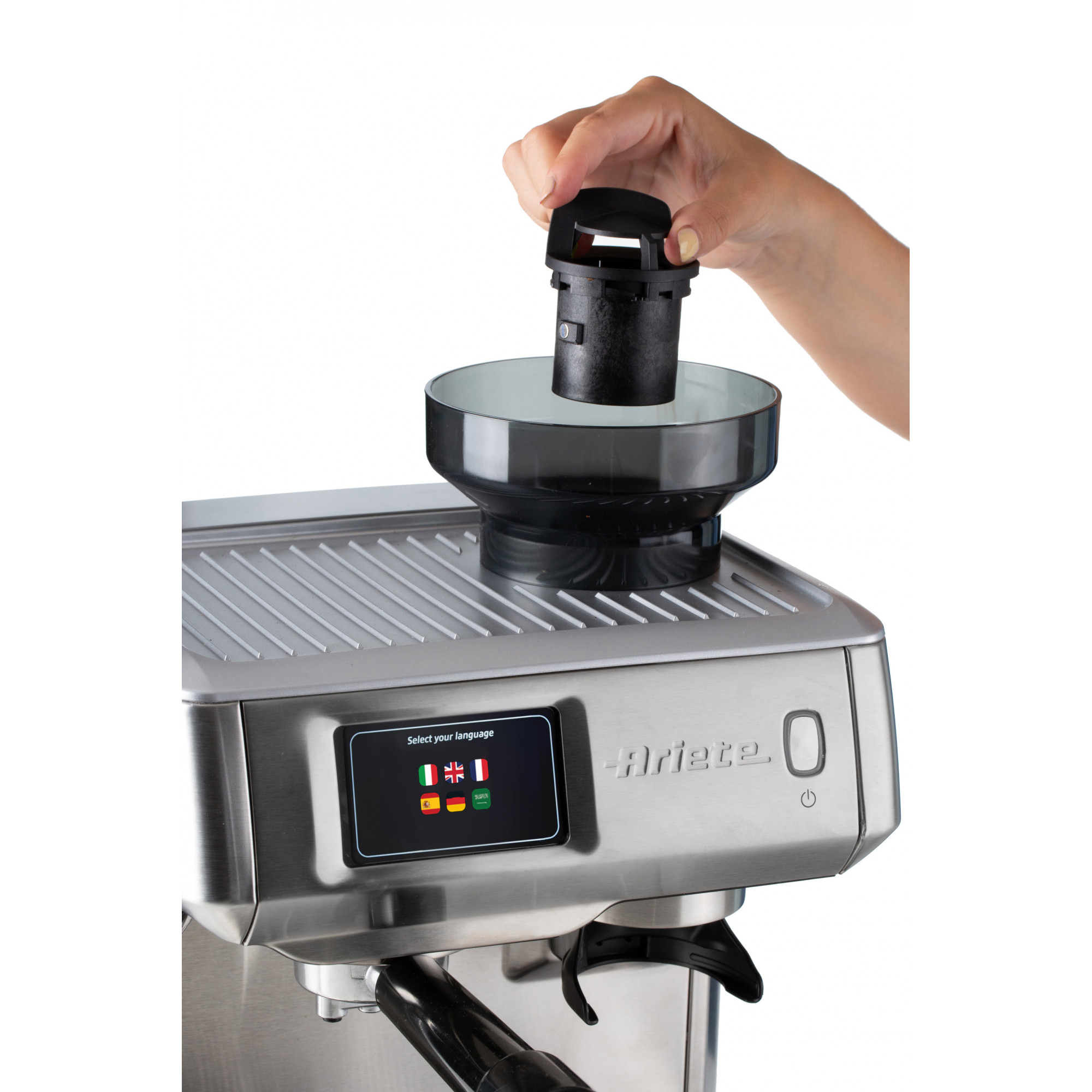 Eine Hand hält einen schwarzen Filter über einer Espressomaschine. Die Maschine ist silber und hat einen Bildschirm.