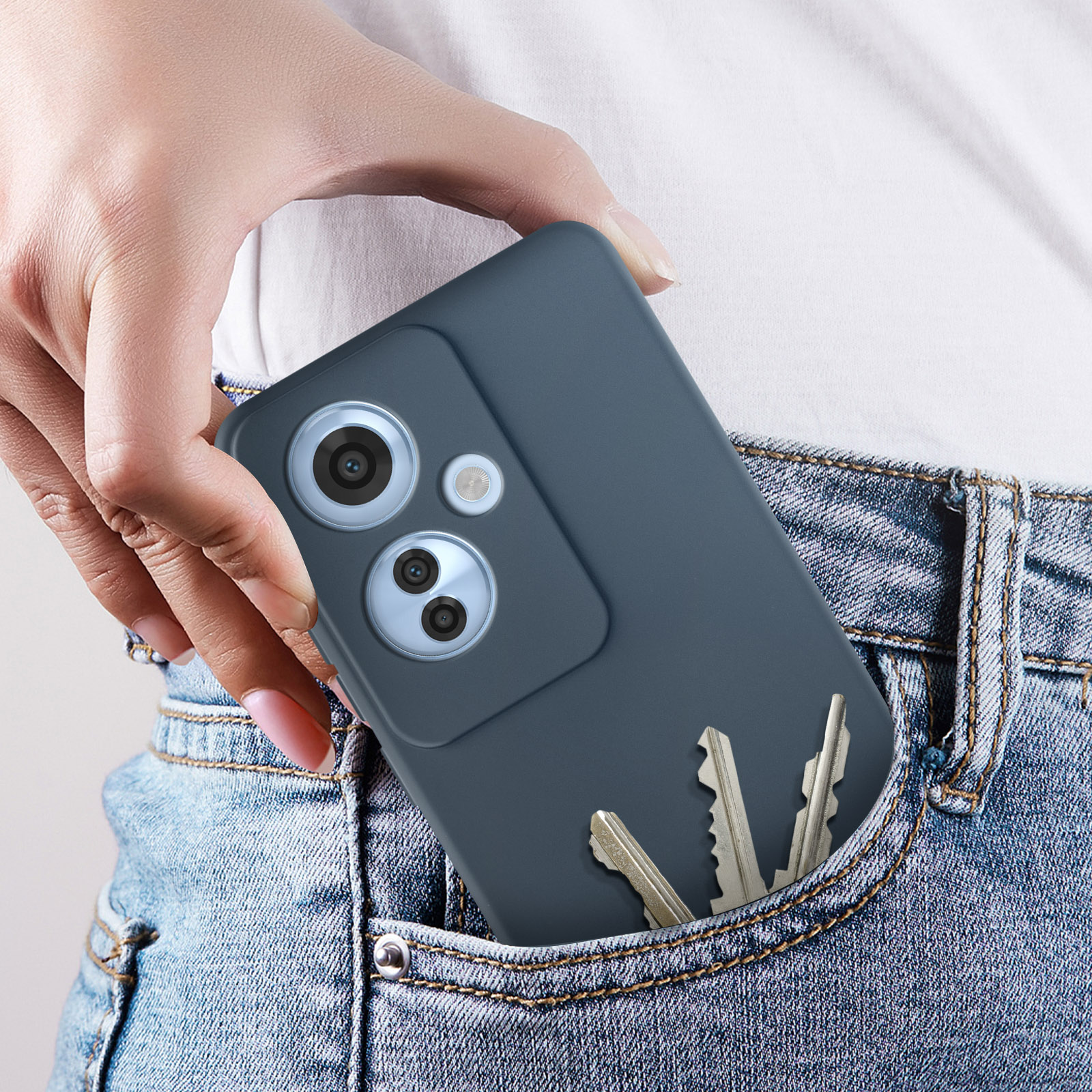 Mano che mette un telefono in tasca dei jeans, con chiavi. Custodia blu e jeans.